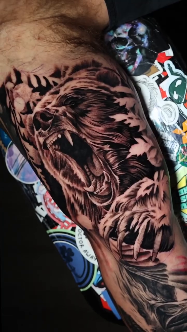 Lion and foliage realism tattoo on the upper arm by Jesus Bravo