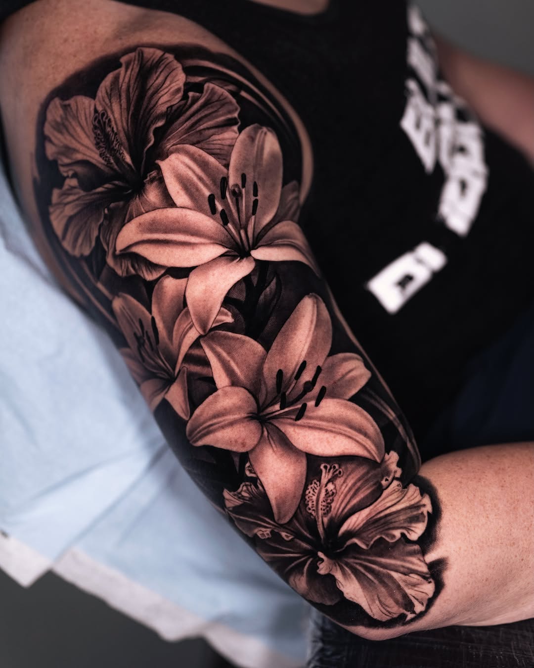 Lilies and hibiscus flowers fine line tattoo on the forearm by Marcos Salamanca