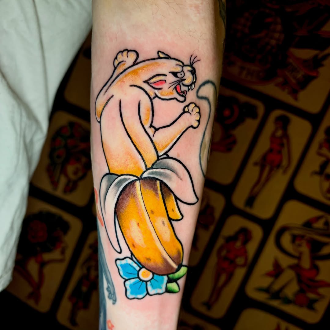 Cat riding banana American traditional tattoo on the forearm by Ashley Lin Las Vegas Tattoo Artist