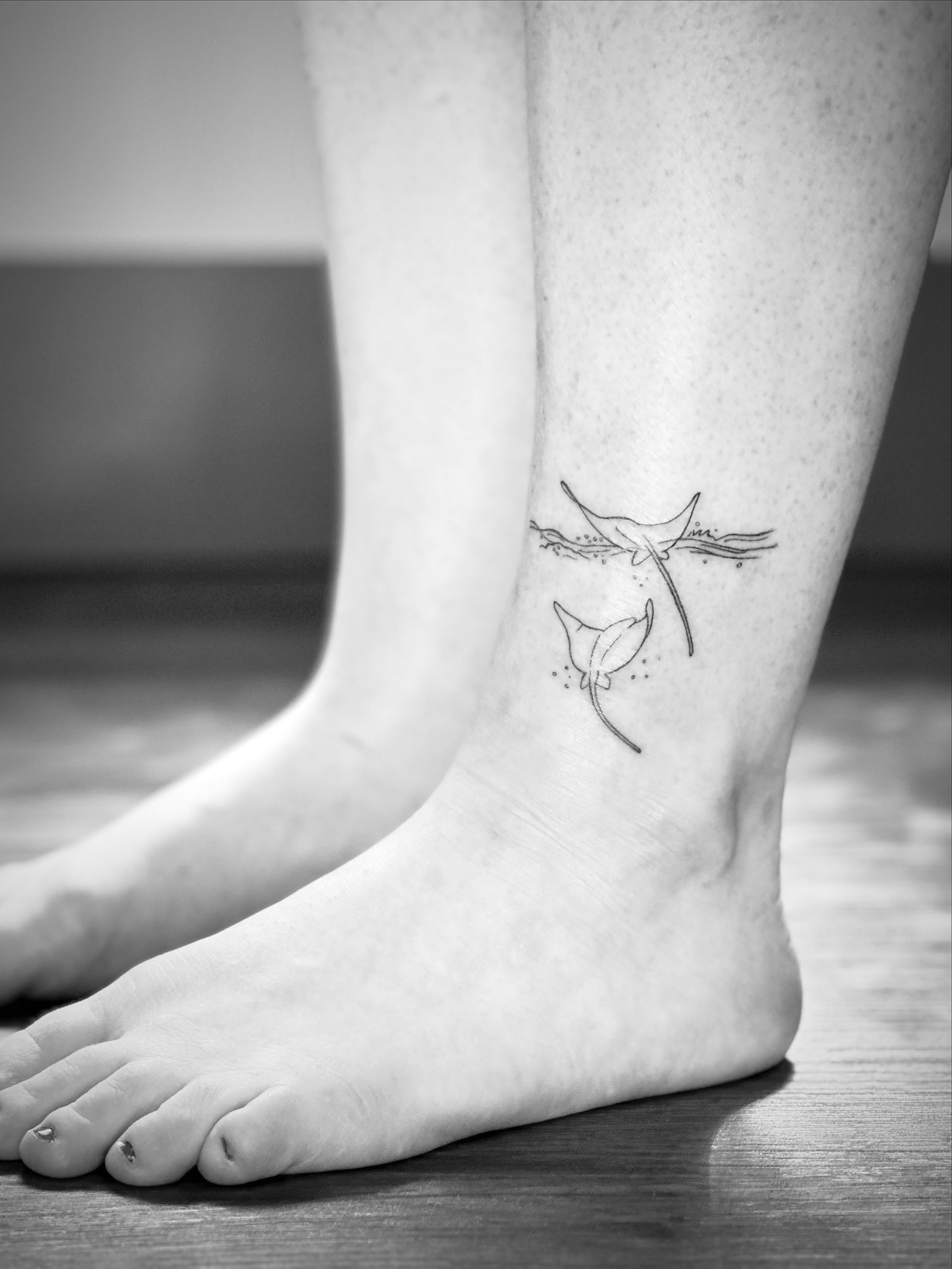 Dolphins and lily black and grey tattoo on the foot by Liz