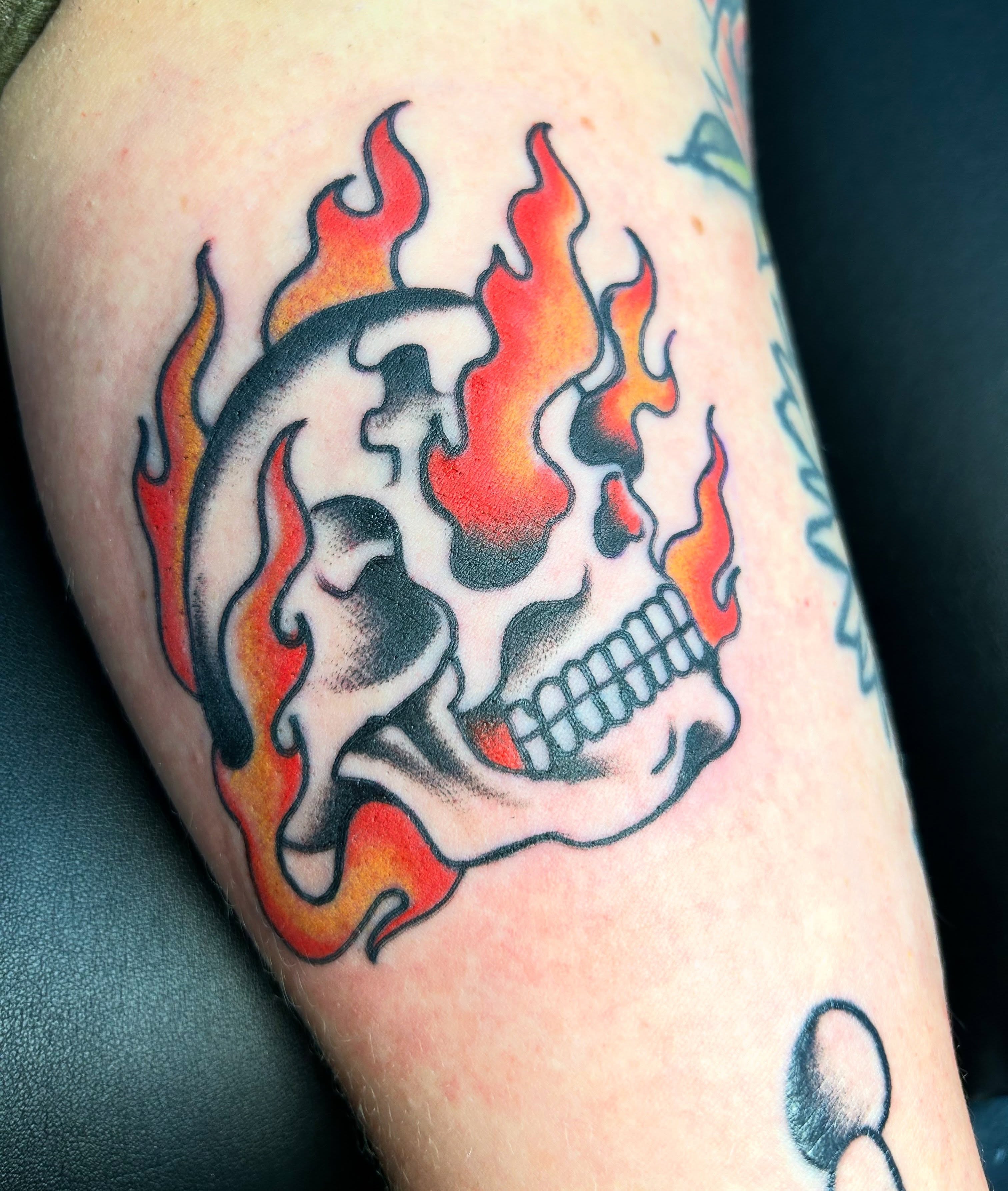 Flaming skull American traditional tattoo on the forearm by Erik Sacony