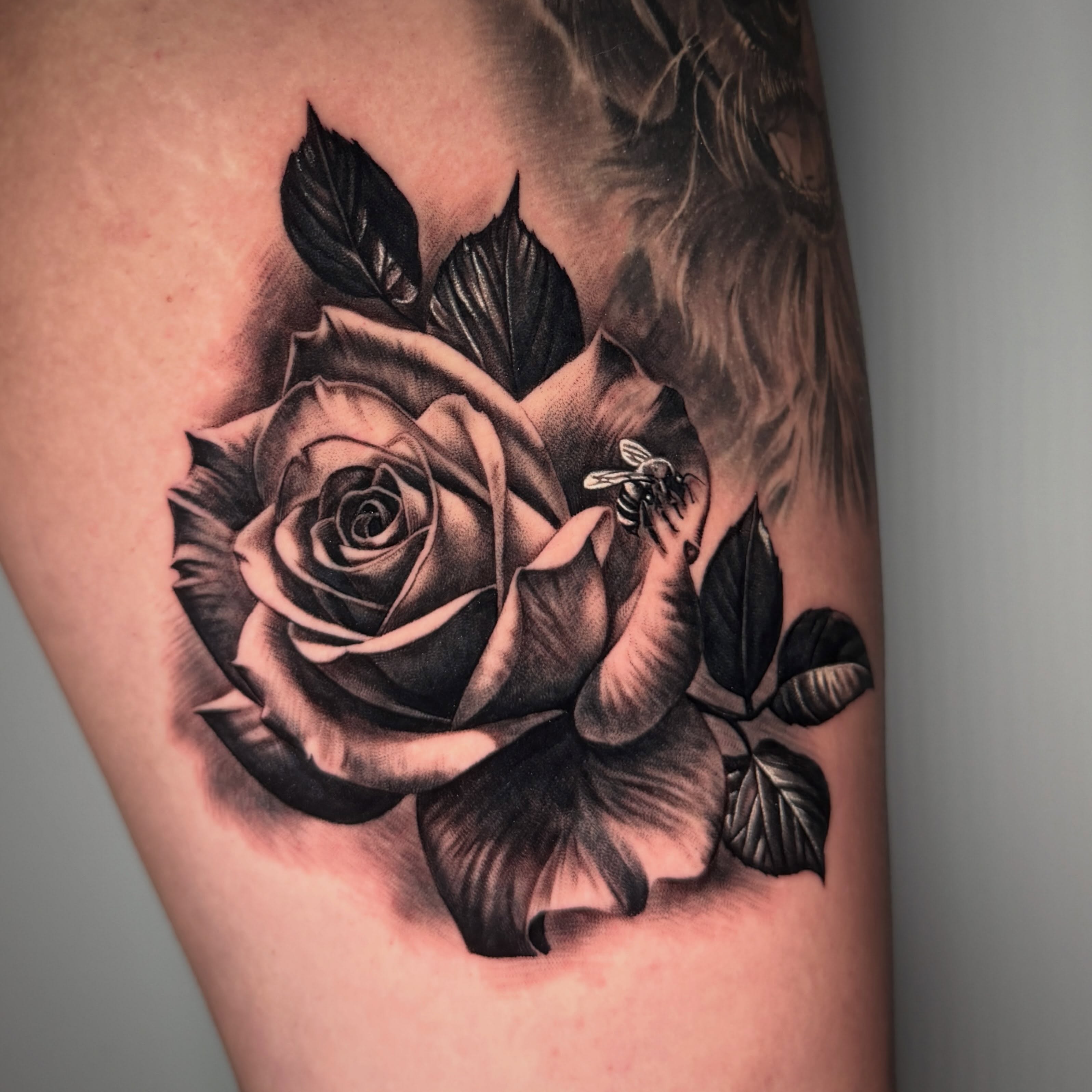 Rose and bee realism tattoo on the thigh by TJ Schunemann