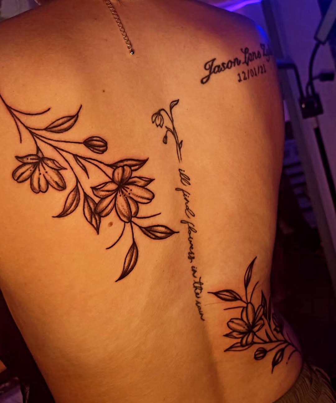 Floral sprigs and script blackwork tattoo on the back by Karley Michelle Moody