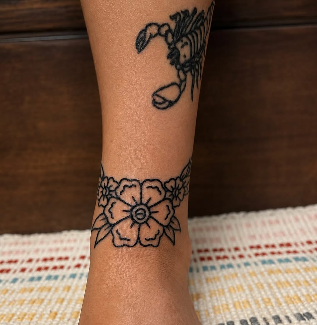 Floral band and scorpion fine line tattoo on the forearm by sams tattoos