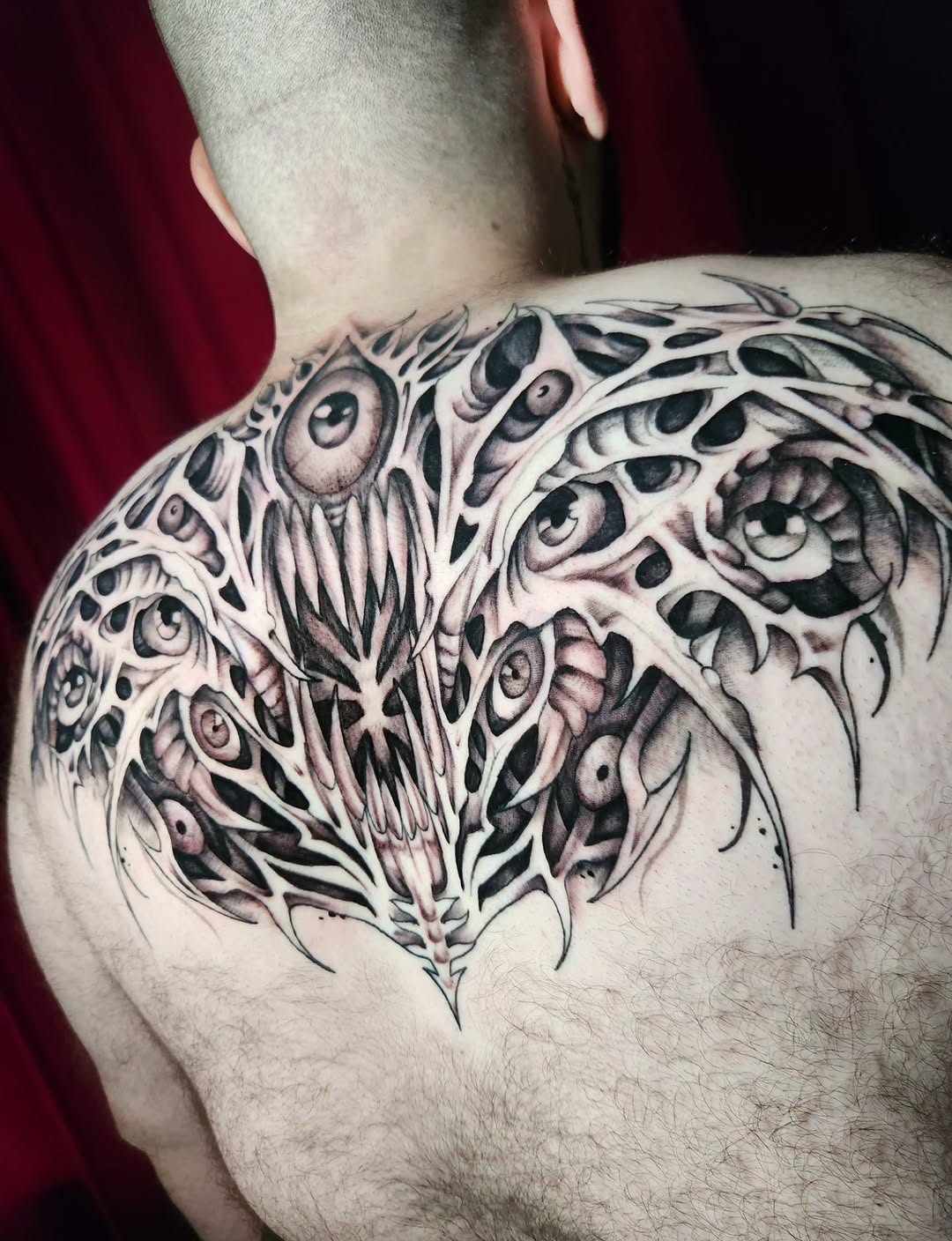 Biomechanical creature face dark art tattoo on the back by Abby Renteria