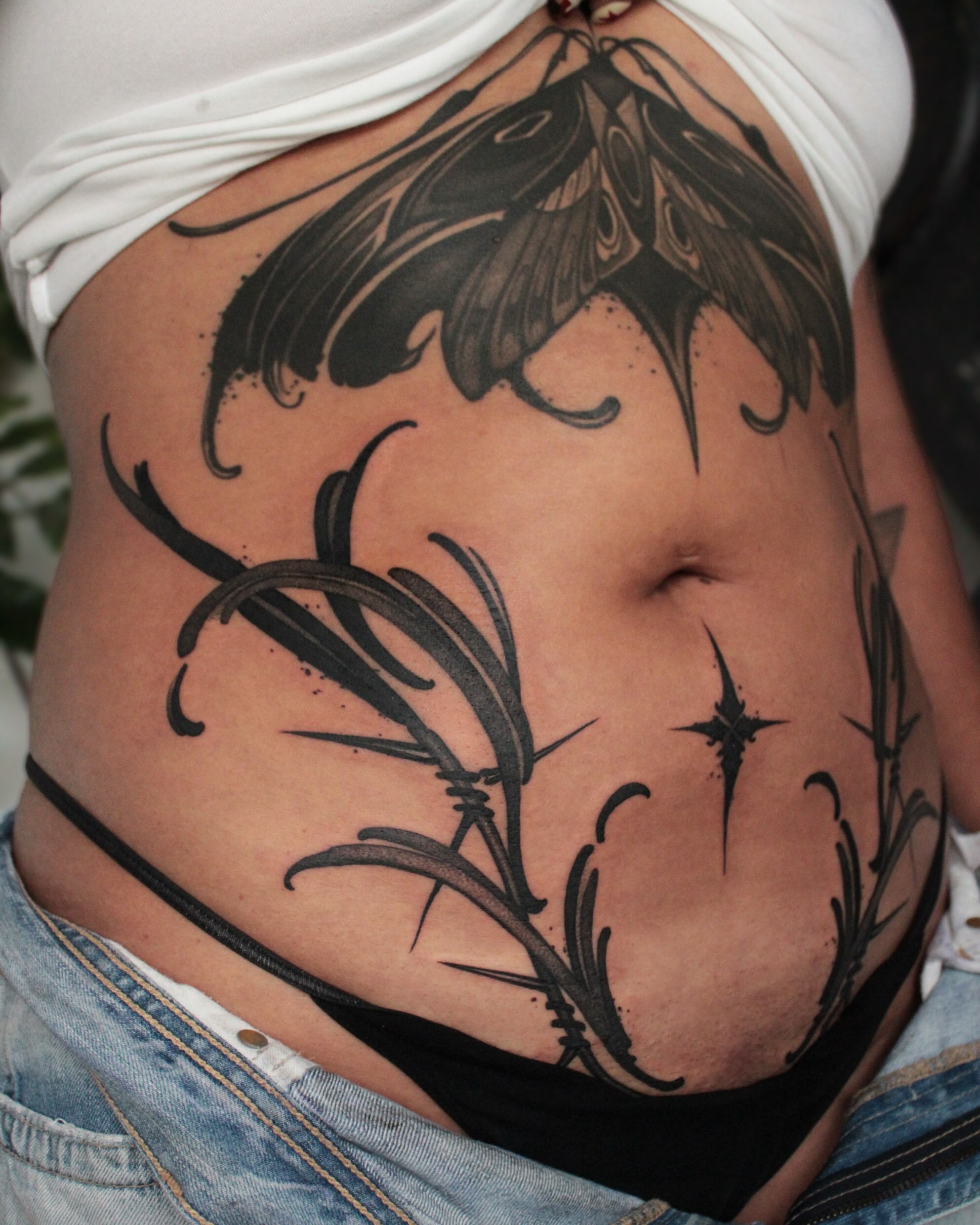 Moth and plant black and grey tattoo on the torso by Heather Apgar