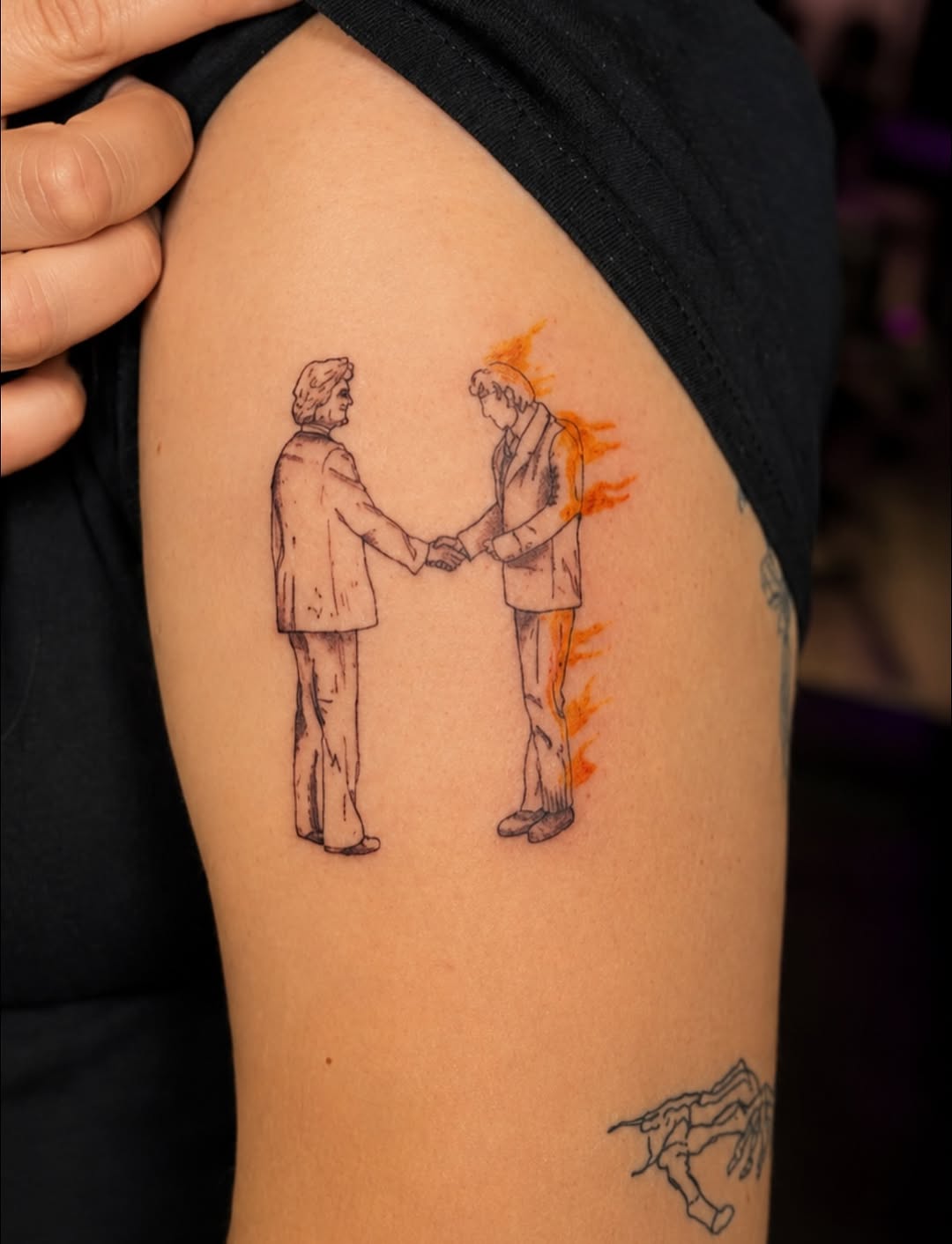 Two men shaking hands with flames ignorant tattoo on the upper arm by Cece, Las Vegas, Nevada