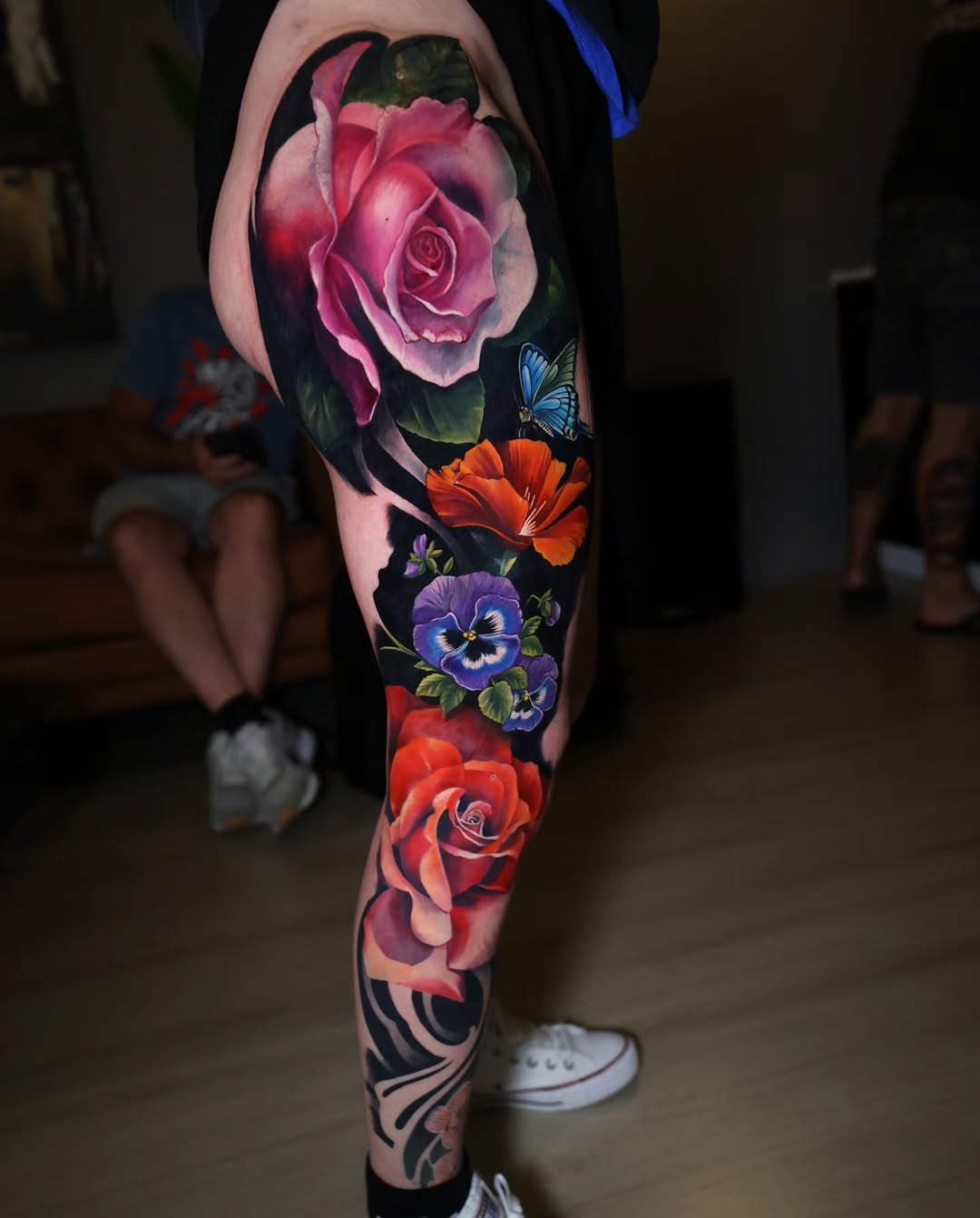 Roses and pansies with butterfly neo-traditional tattoo on the leg by Marek Pawlik