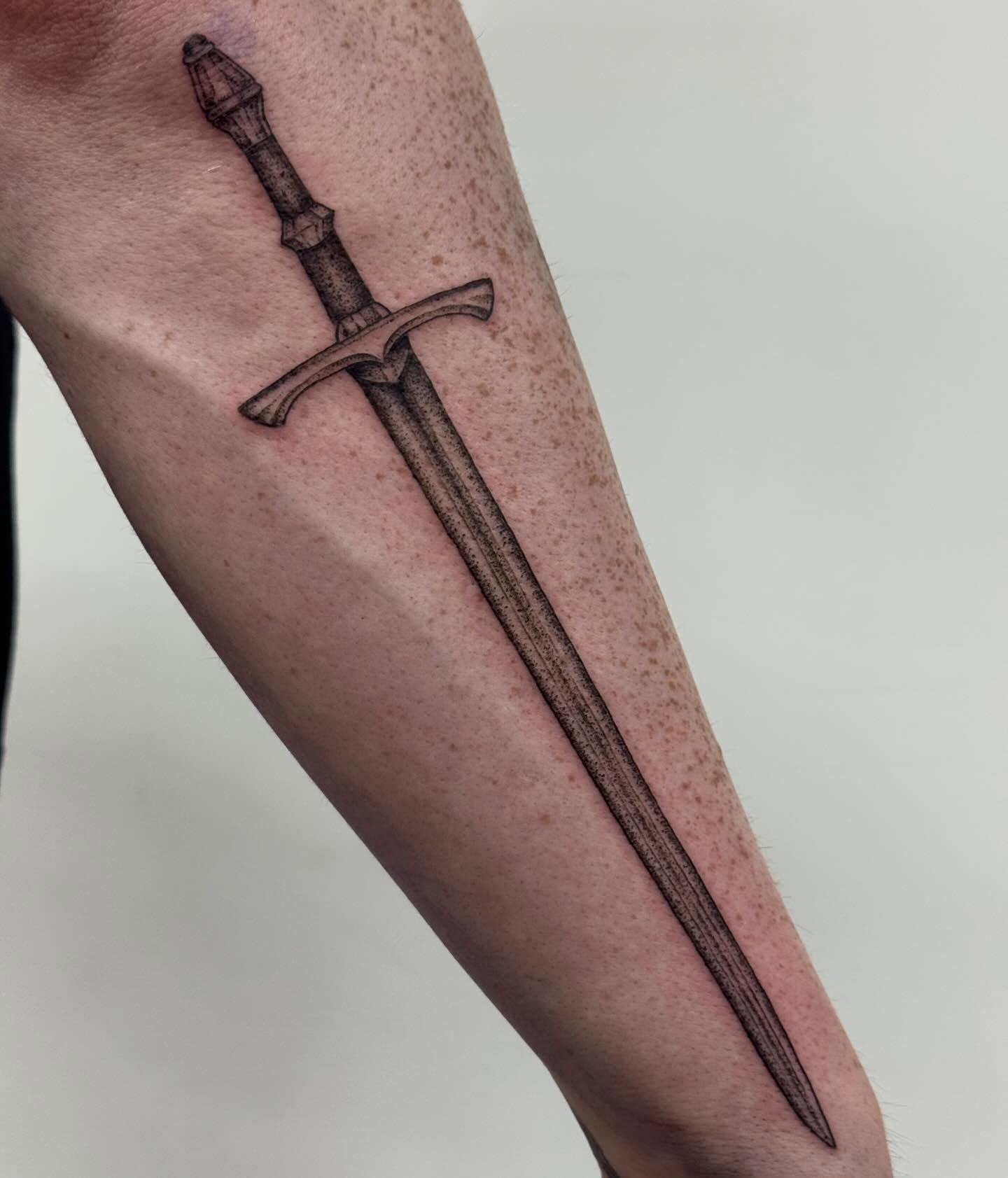 Sword black and grey tattoo on the forearm by Writhe Grey