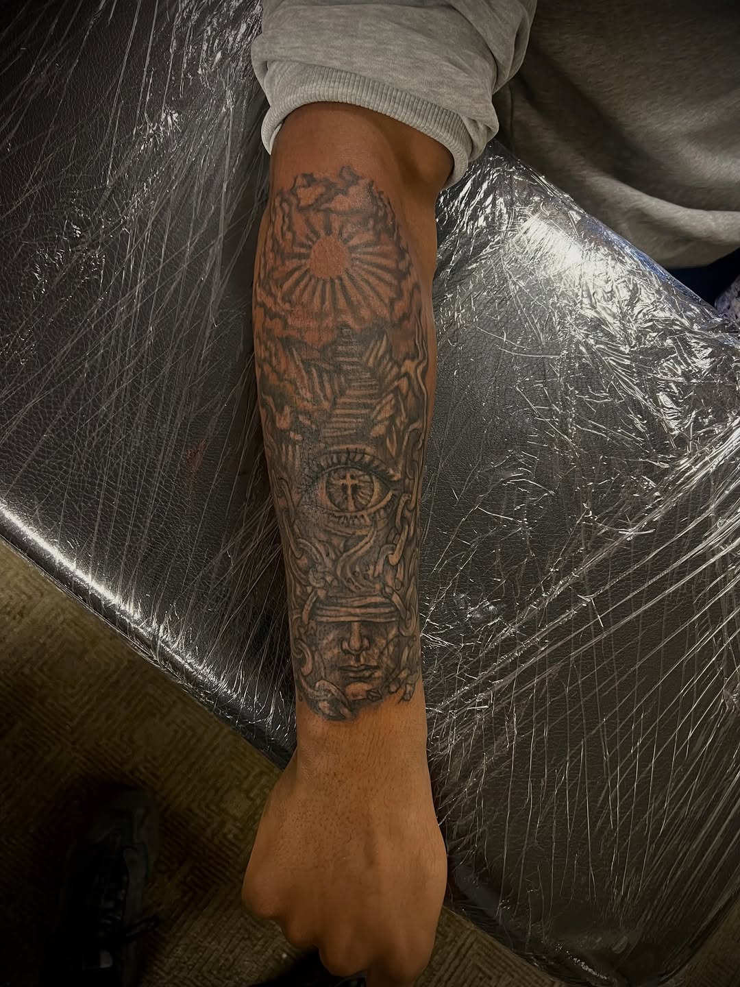 Eye of providence and face realism tattoo on the forearm by Jelani