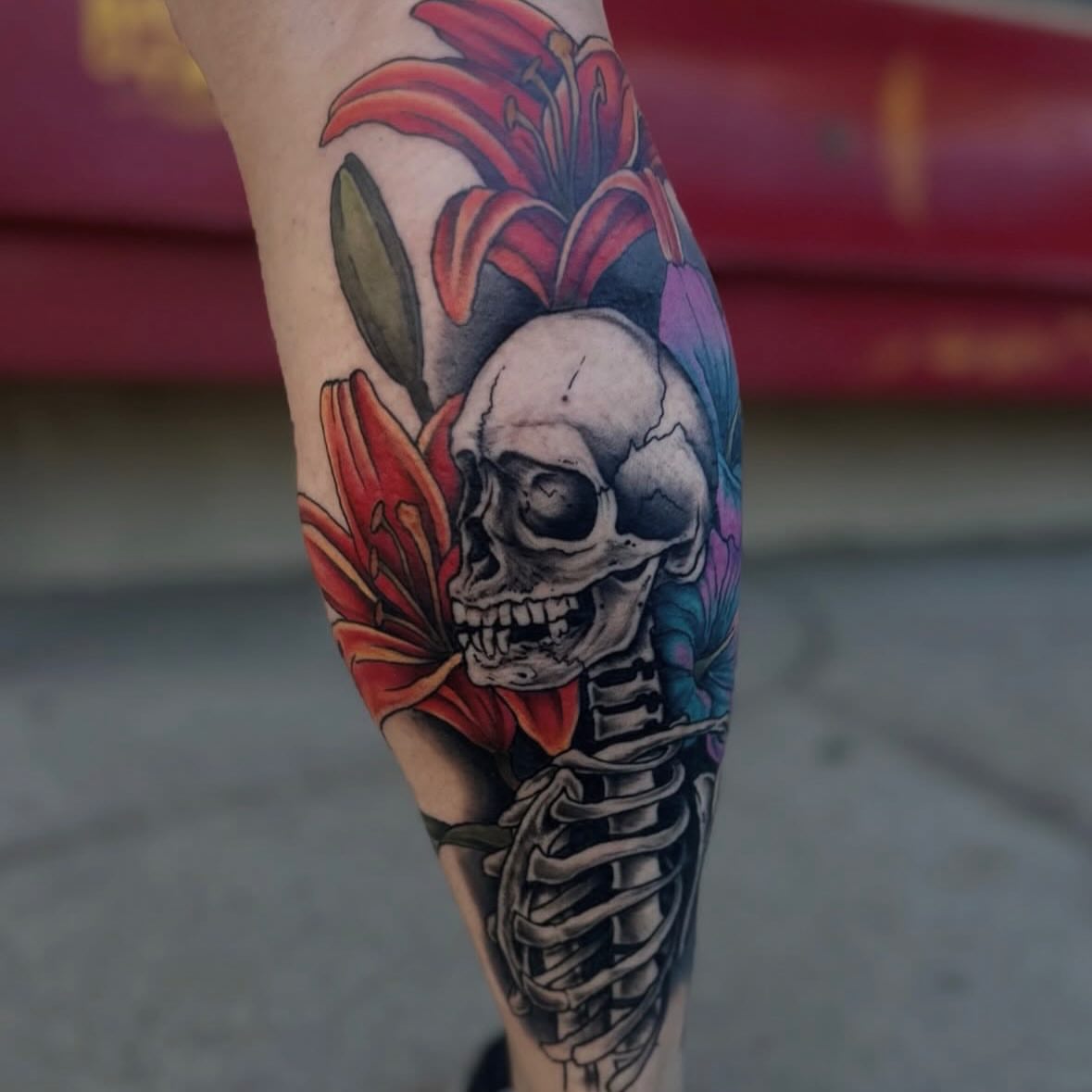 Skull and flowers realism tattoo on the forearm by Josh Kronauer
