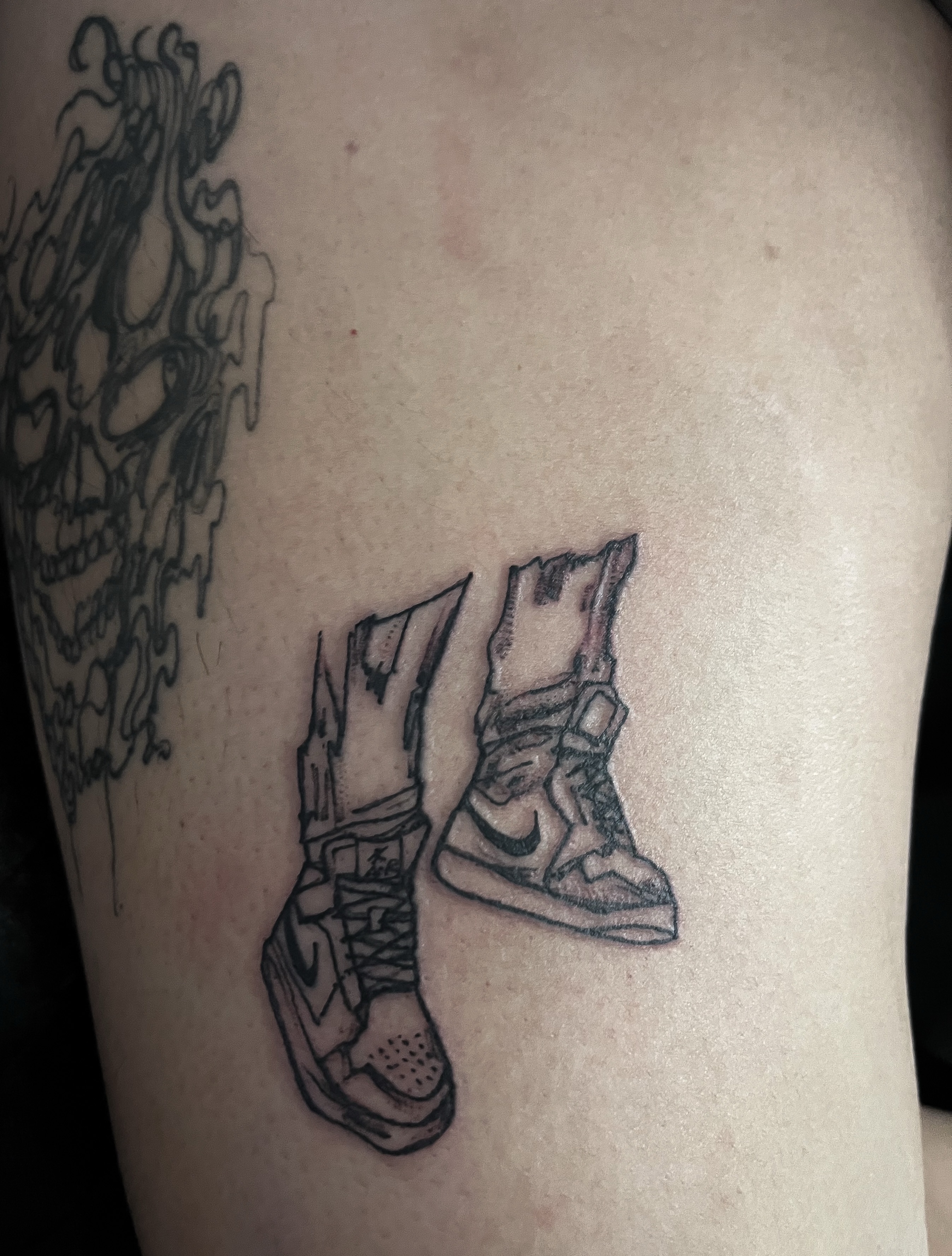 Sneakers black and grey tattoo on the thigh by Janelle Cuba
