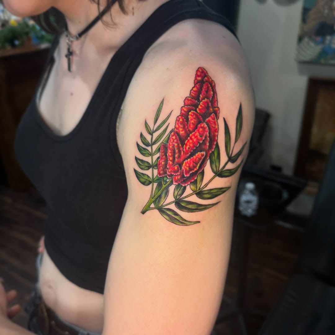 Red flower realism tattoo on the upper arm by Lily Nurnberger
