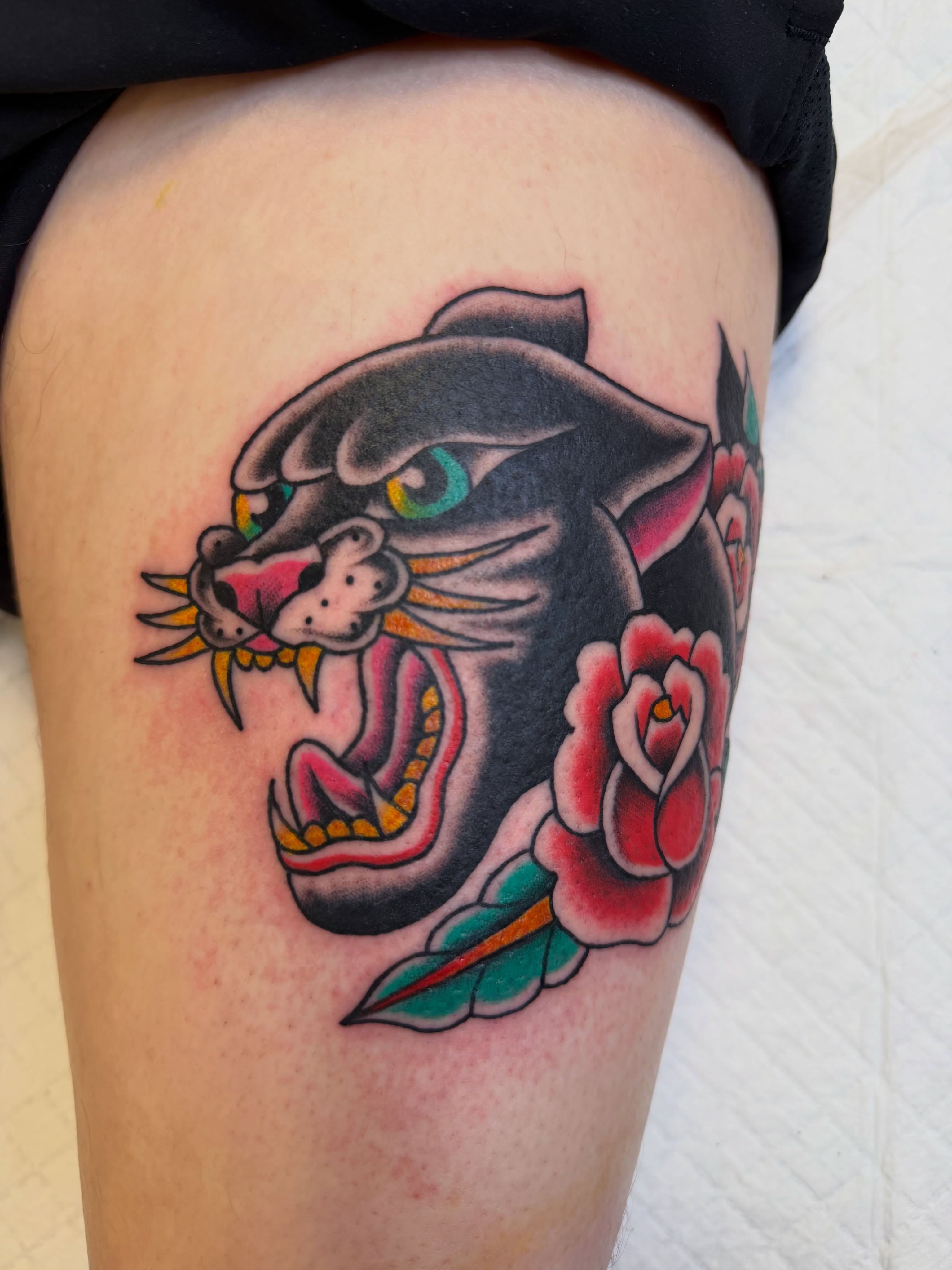 Panther and rose American traditional tattoo on the thigh by Nick Tumminello