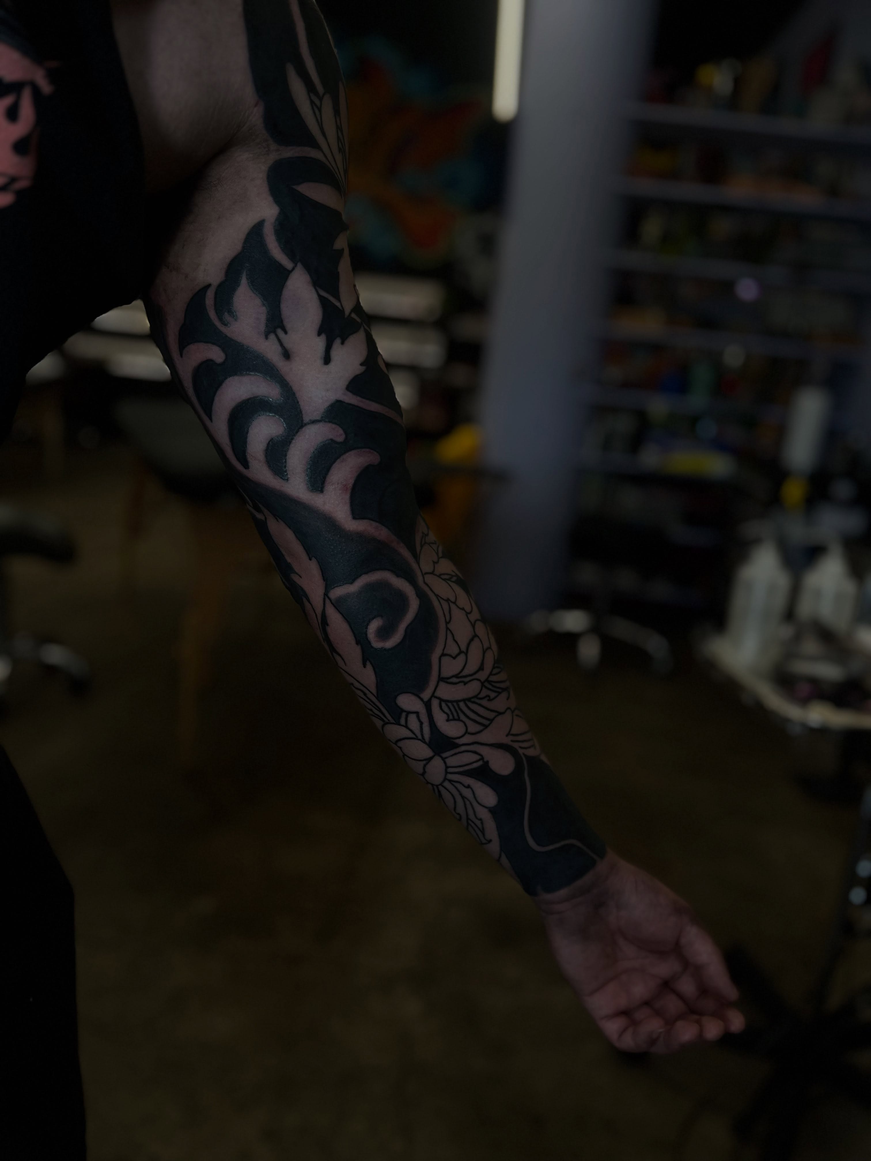 Flame and floral black and grey tattoo on the forearm by Kaichi Fujita, Eugene, Oregon