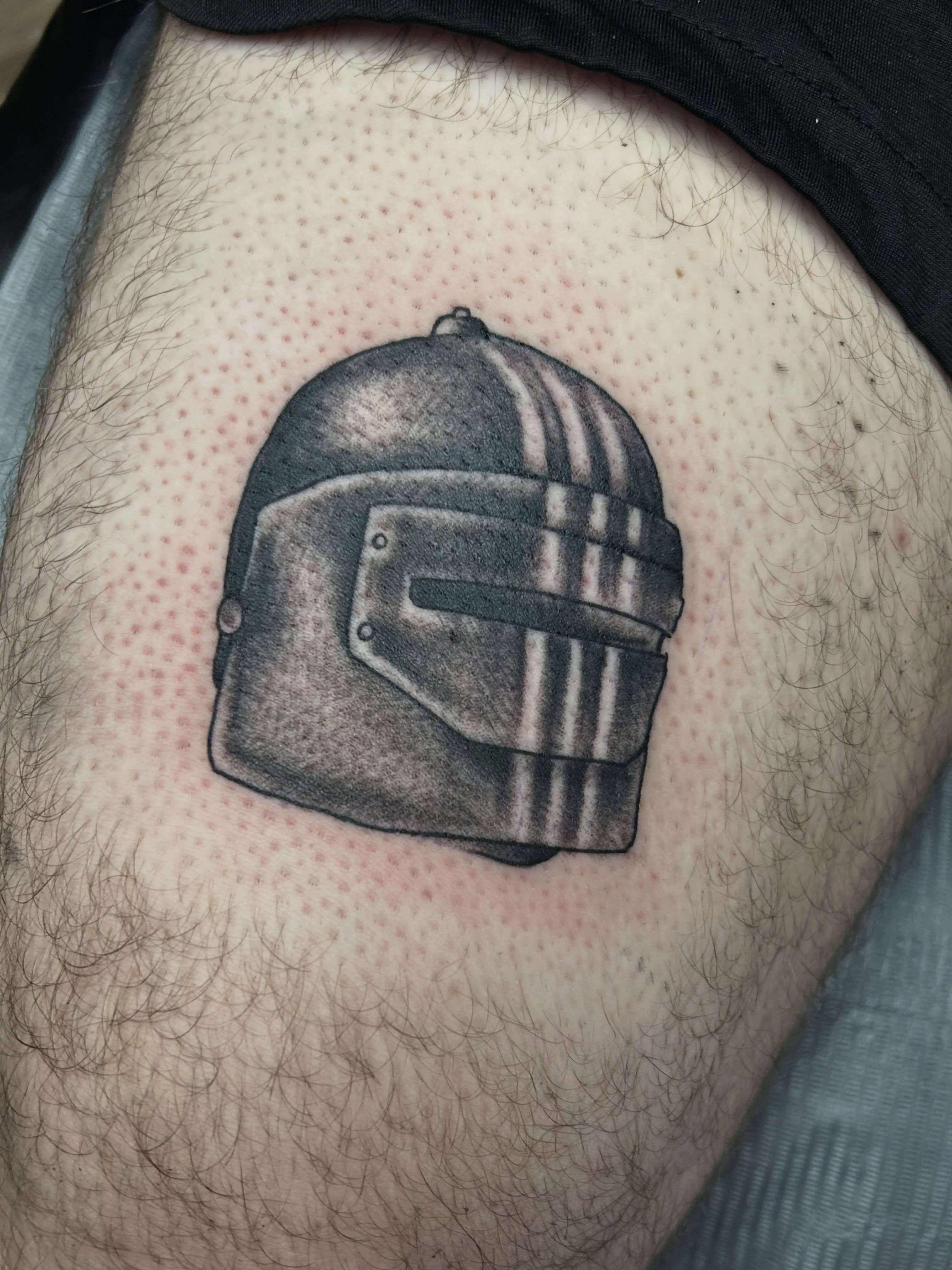 Helmet black and grey tattoo on the thigh by Dan Schuster