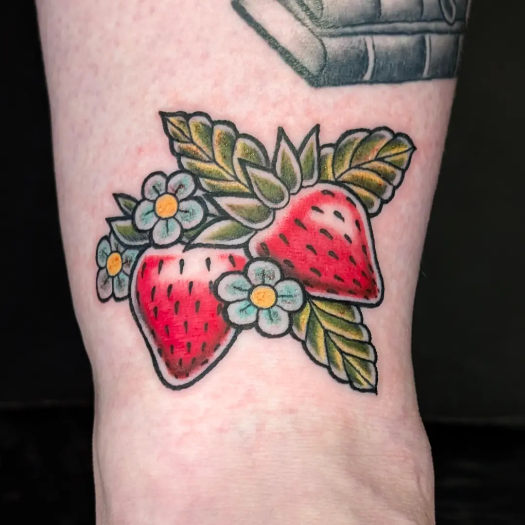 Strawberries and flowers American traditional tattoo on the forearm by Gina Carlson