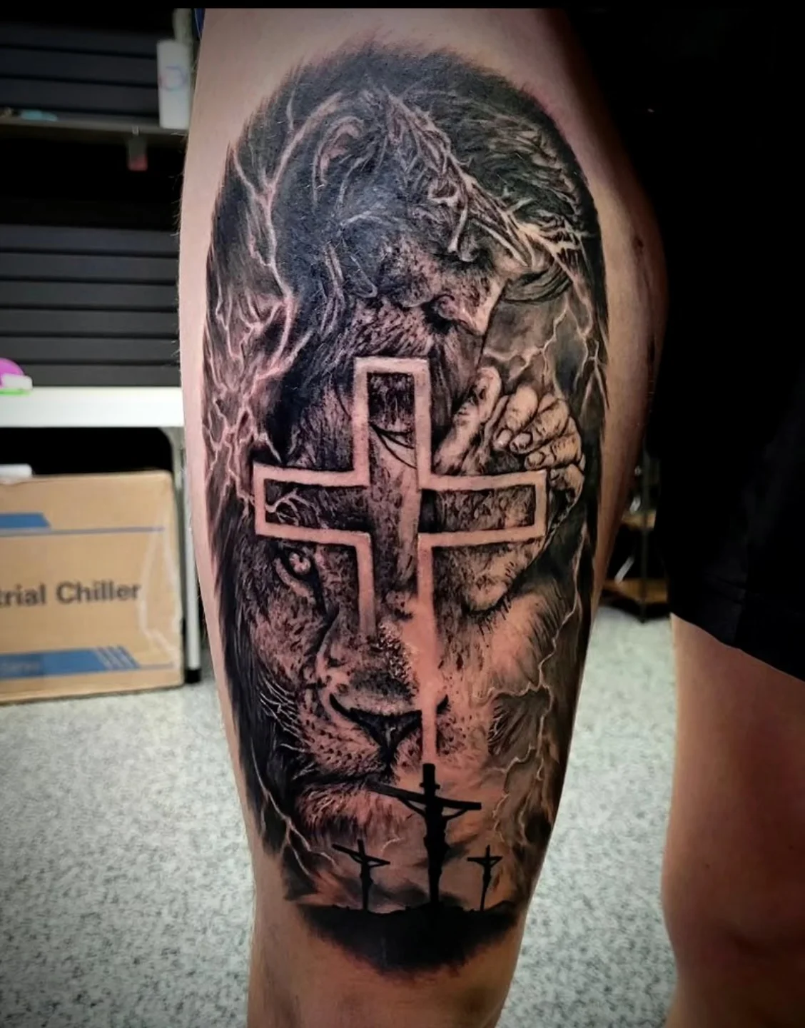 Lion and cross realism tattoo on the thigh by Drew King