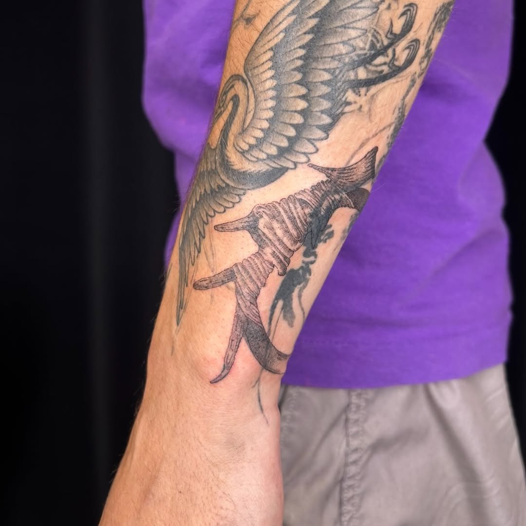 Barbed wire and crane minimalist tattoo on the forearm by Jadin Nichols