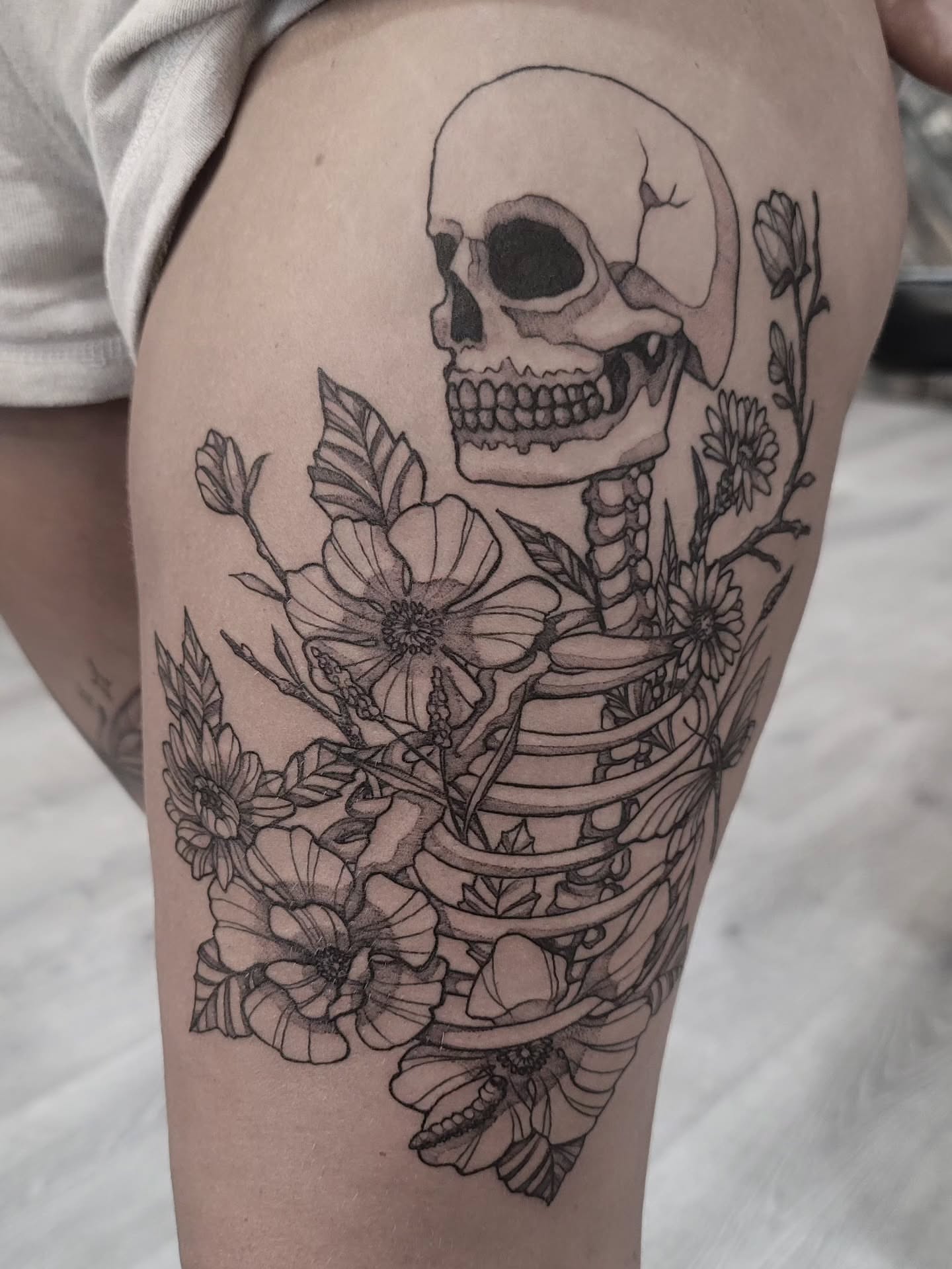 Skull and flowers realism tattoo on the thigh by Tricky Lake, Newfield, New Jersey