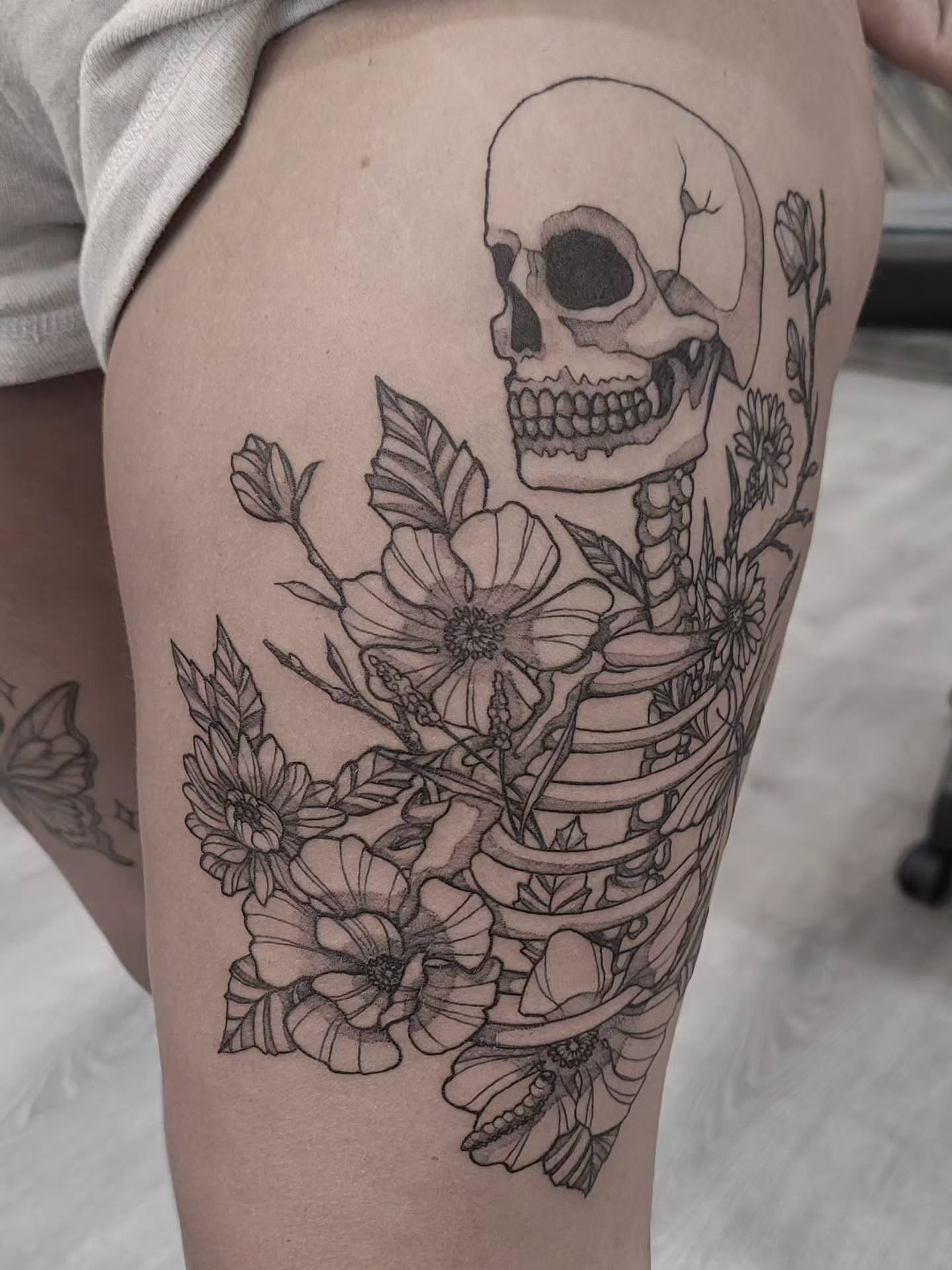 Skull and flowers realism tattoo on the thigh by Tricky Lake, Newfield, New Jersey