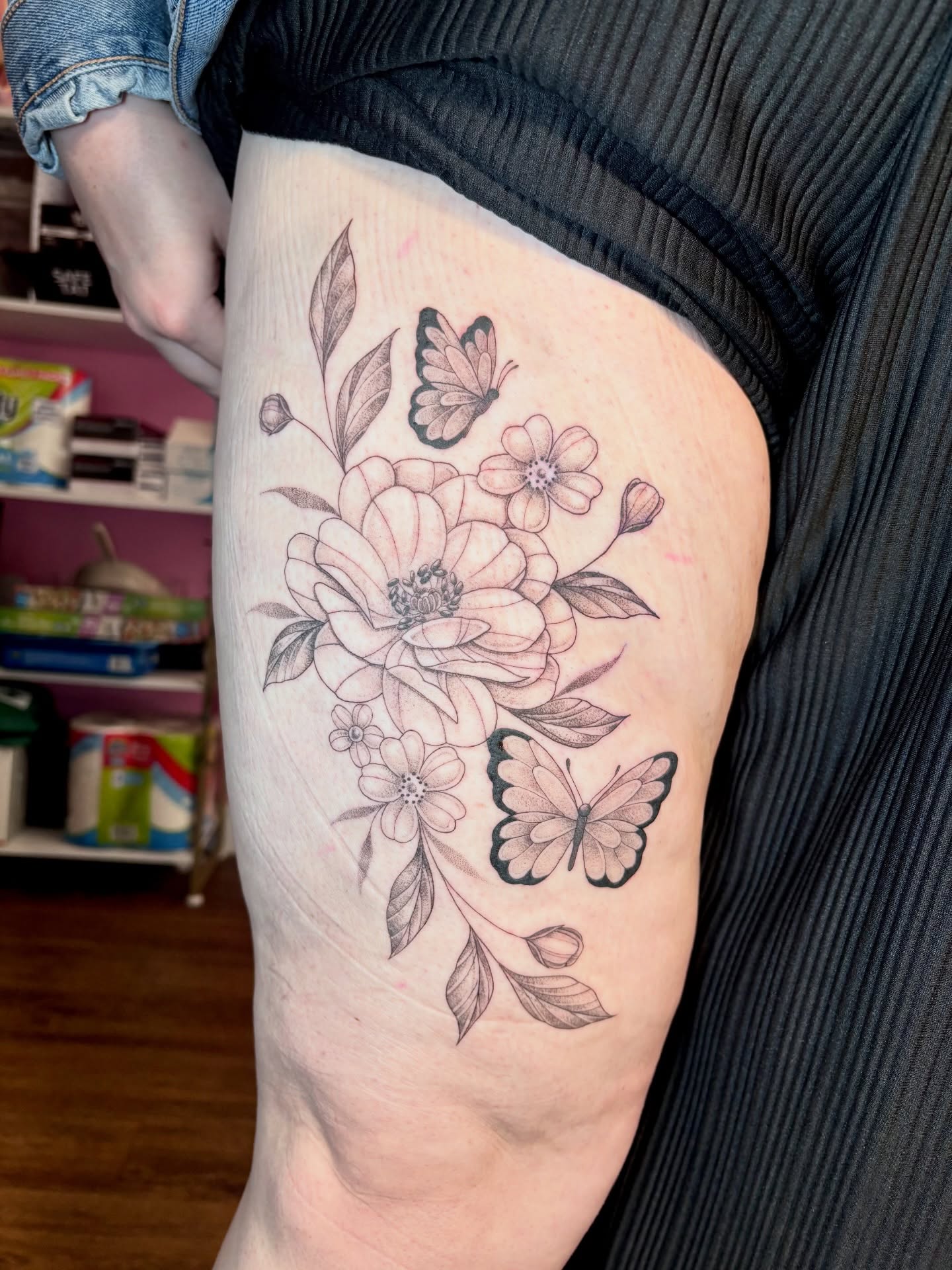 Floral bouquet with butterflies black and grey tattoo on the thigh by Charlotte Brown, Leeds, England