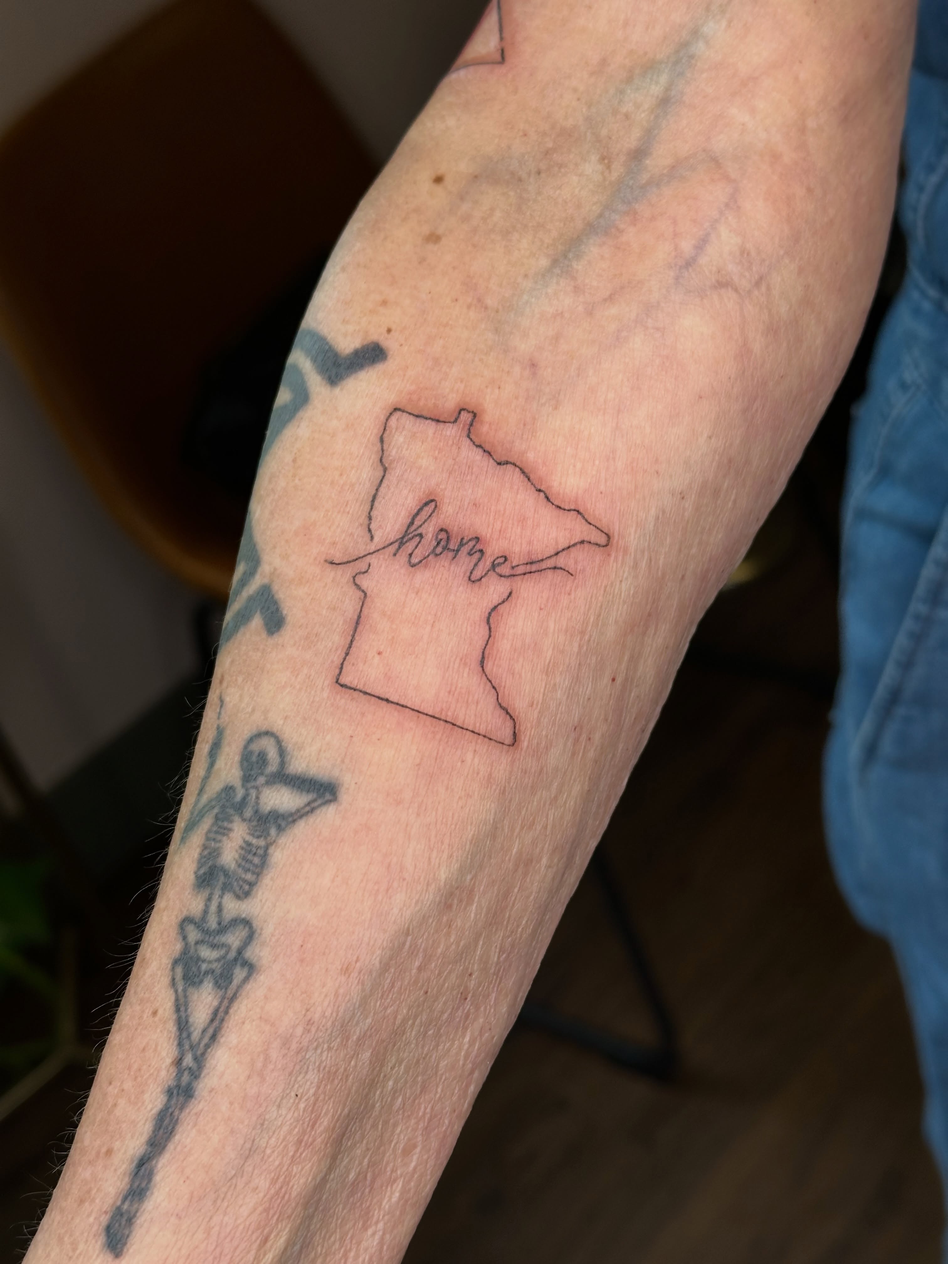 Map outline fine line tattoo on the forearm by Liz