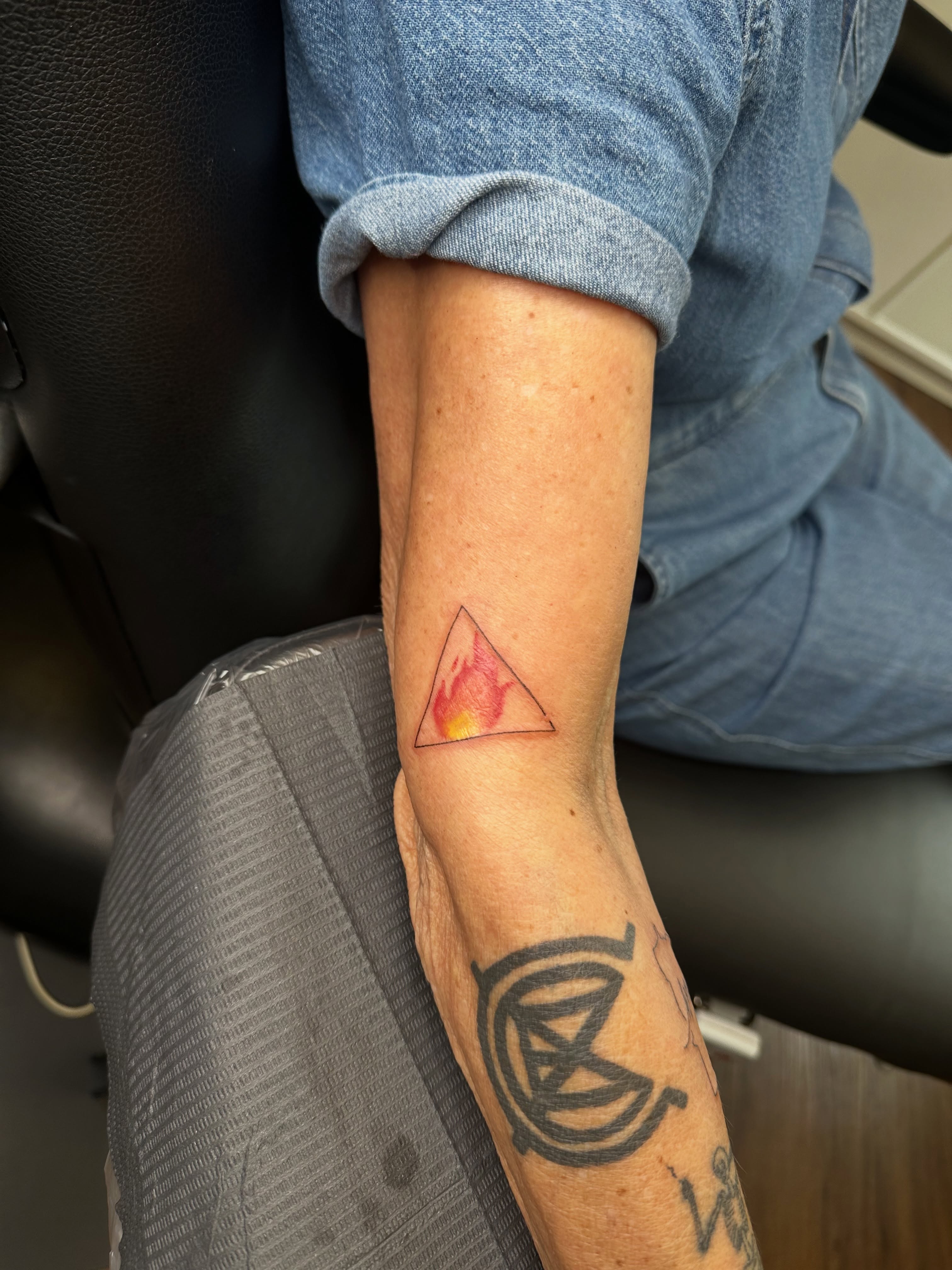 Triangle with flame geometric tattoo on the forearm by Liz