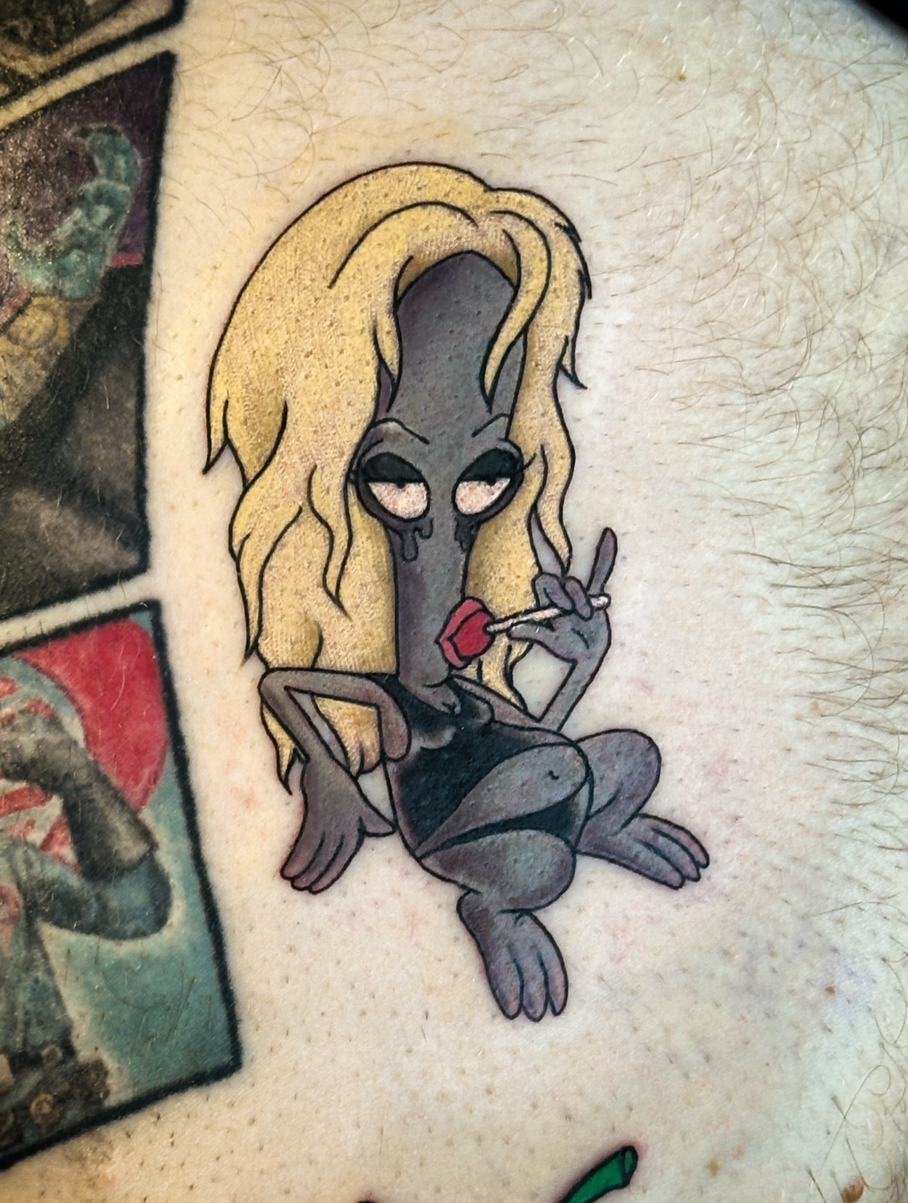 Alien with blonde hair illustrative tattoo on the thigh by Victoria