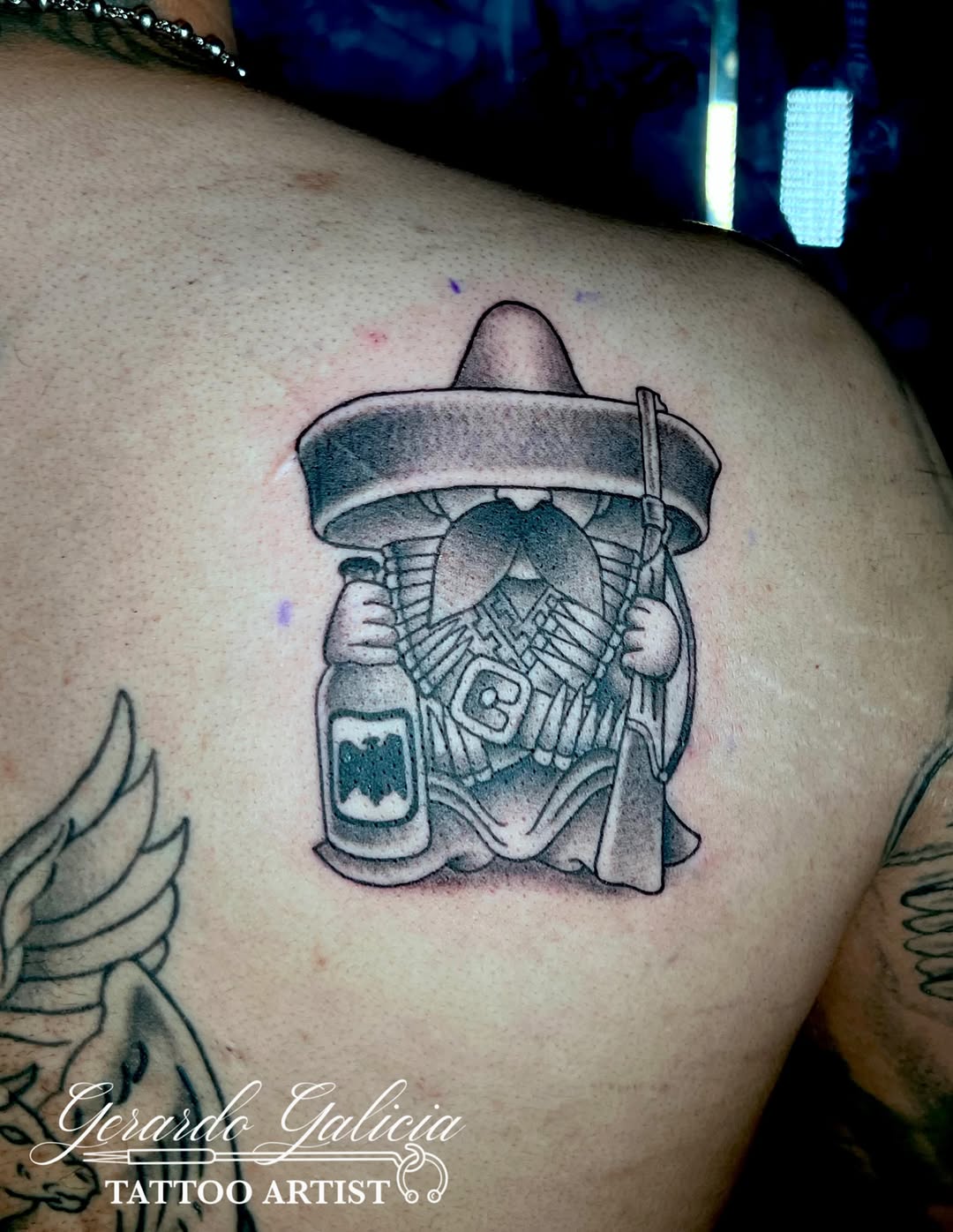 Character with rifle and bottle tattoo on the shoulder by Gerardo Galicia, New York, New York
