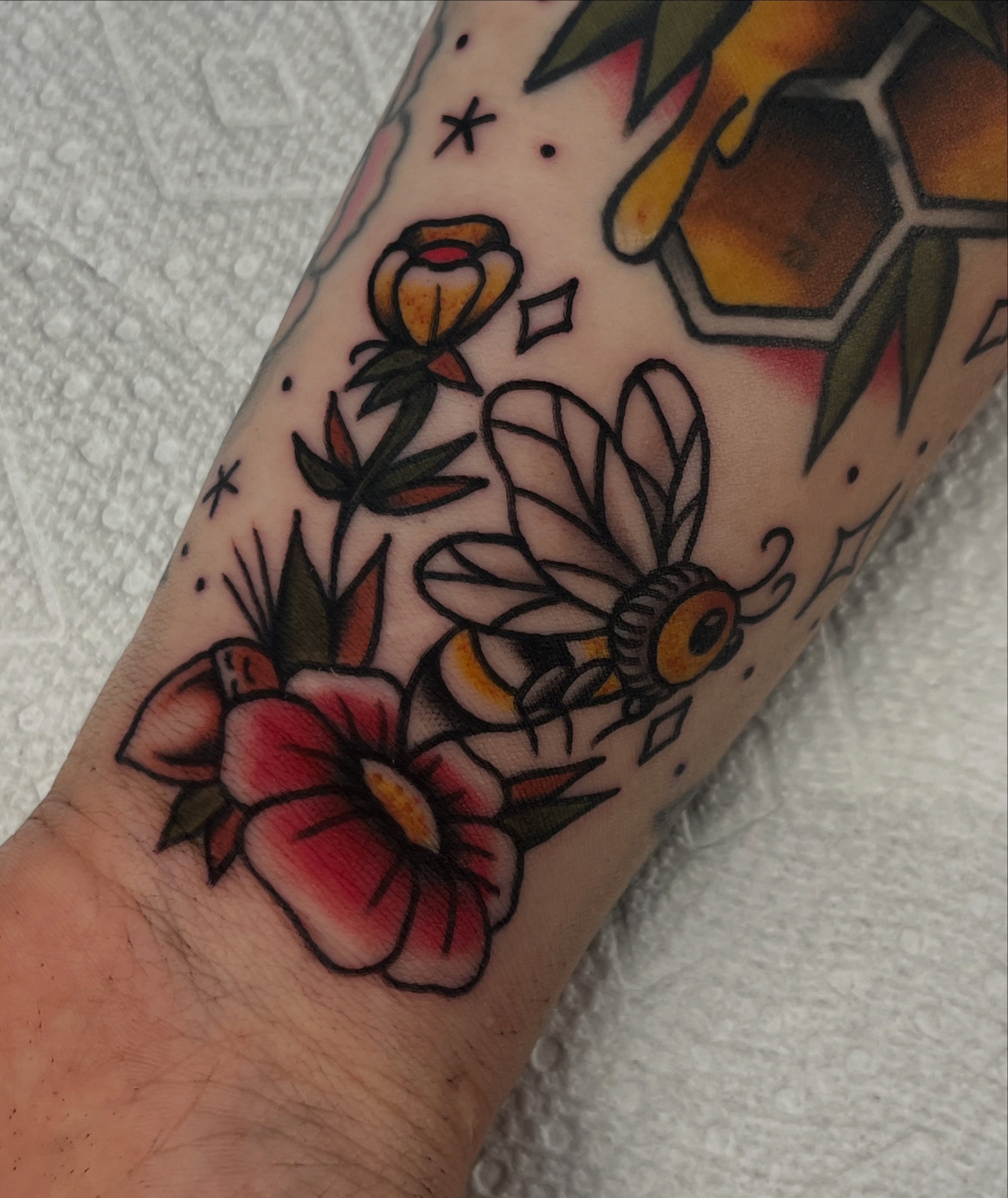 Flowers and bee American traditional tattoo on the forearm by August B., Renton, Washington