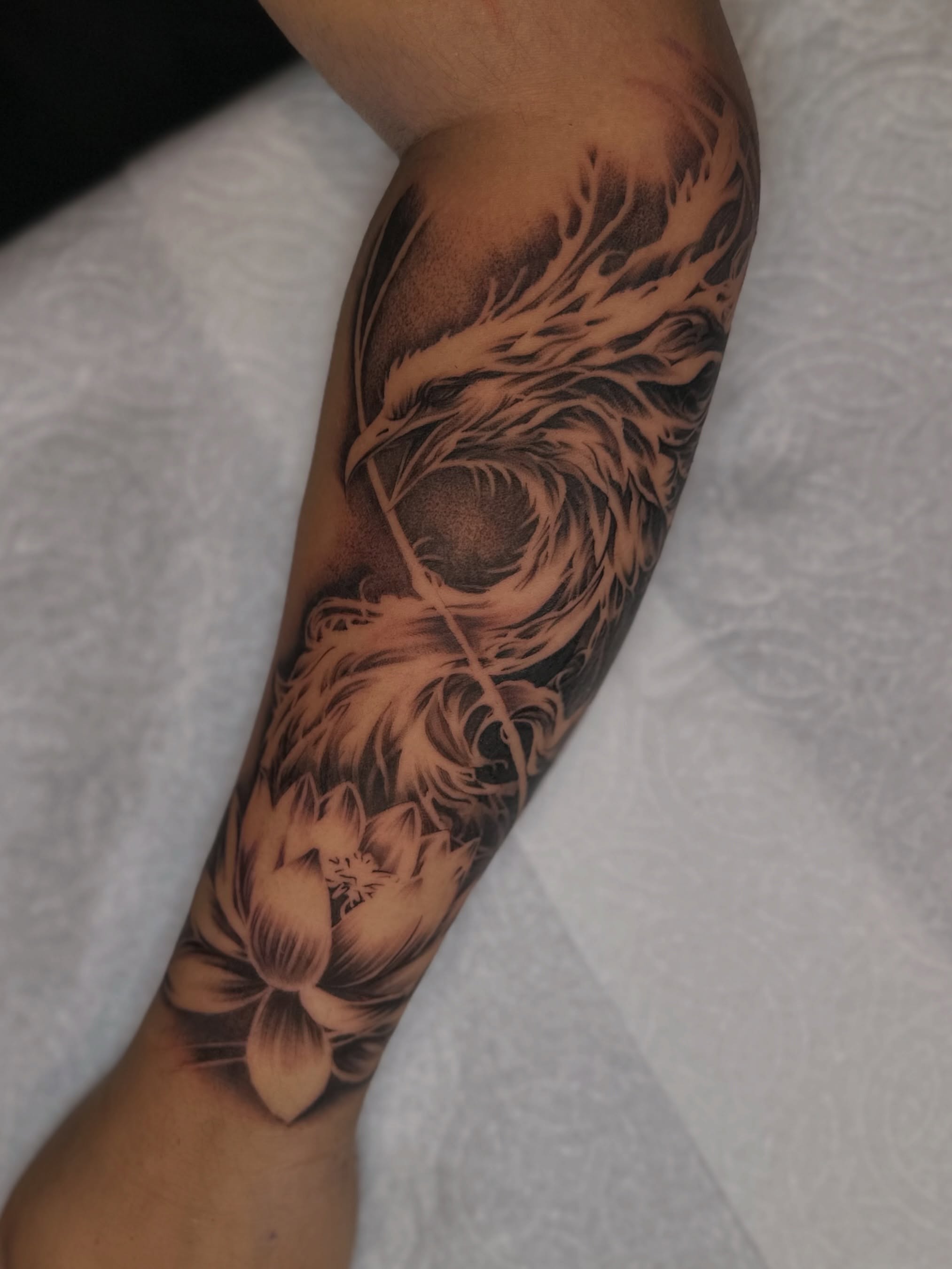 Feather and lotus realism tattoo on the forearm by Mando