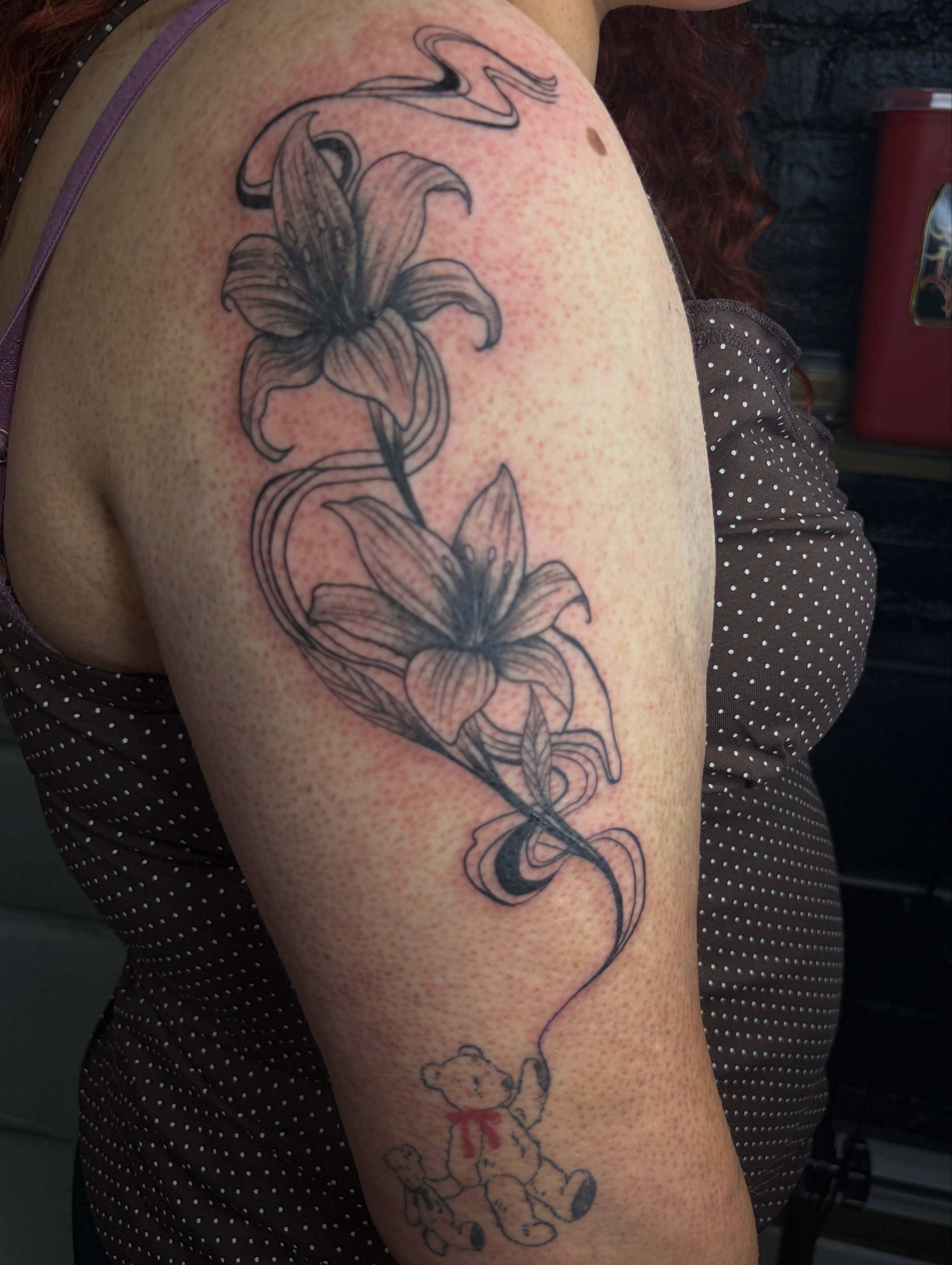 Lilies black and grey tattoo on the upper arm by Destineé