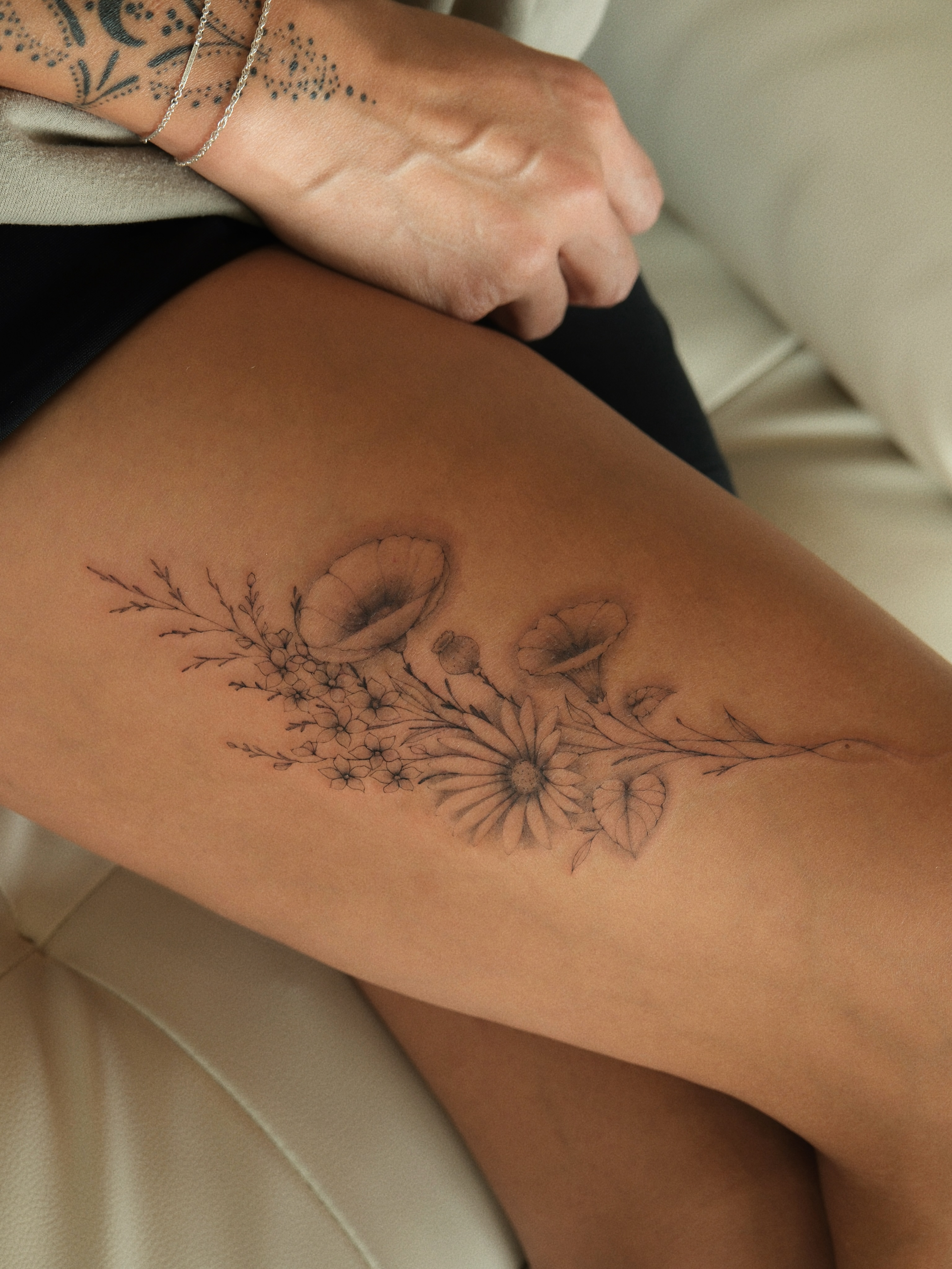 Floral arrangement black and grey tattoo on the thigh by Victoria