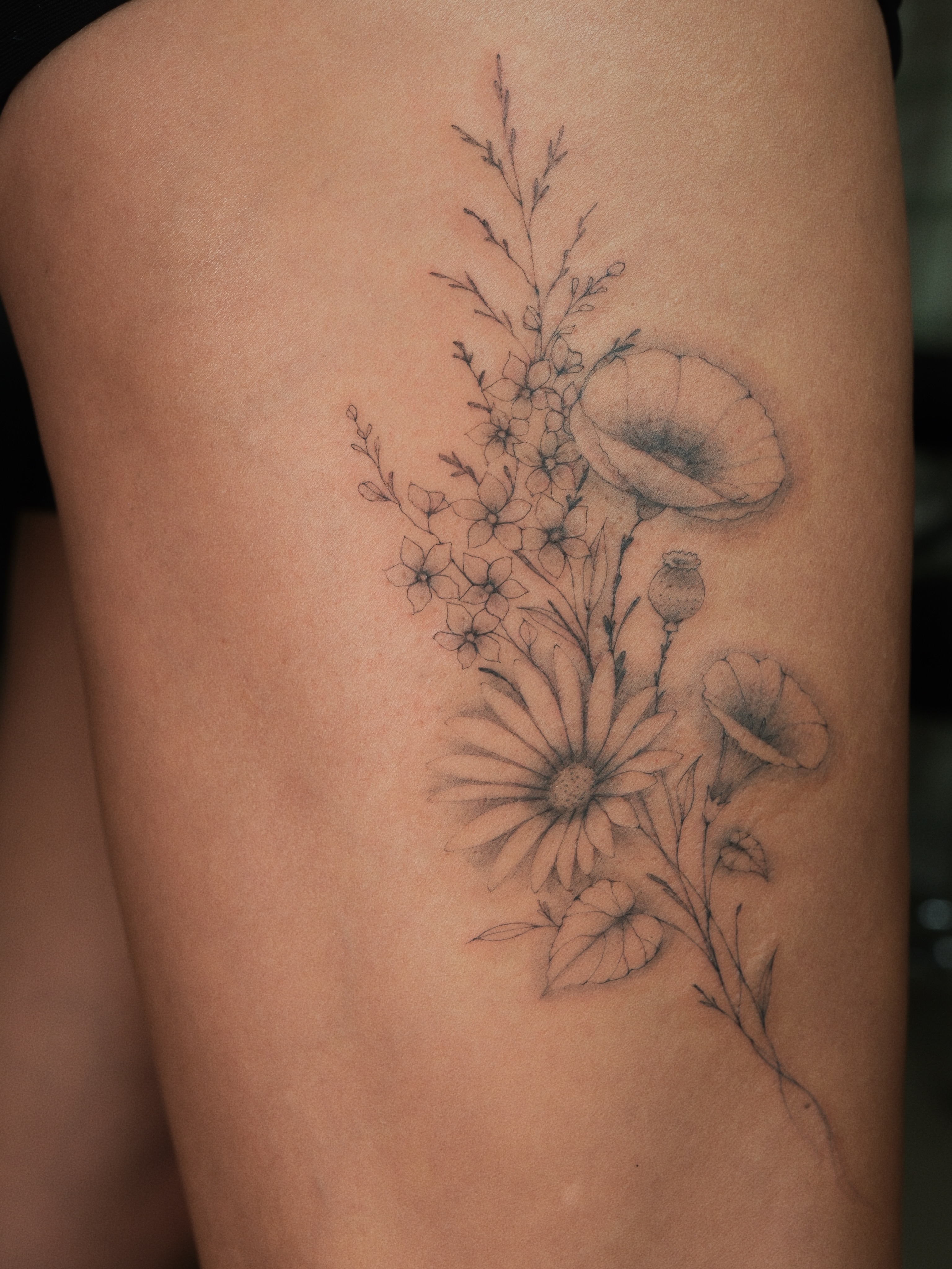 Floral bouquet black and grey tattoo on the thigh by Victoria