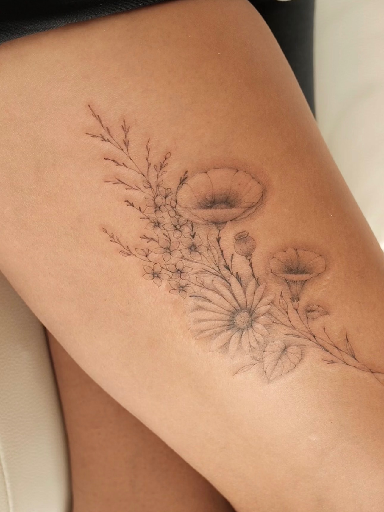 Floral bouquet black and grey tattoo on the thigh by Victoria