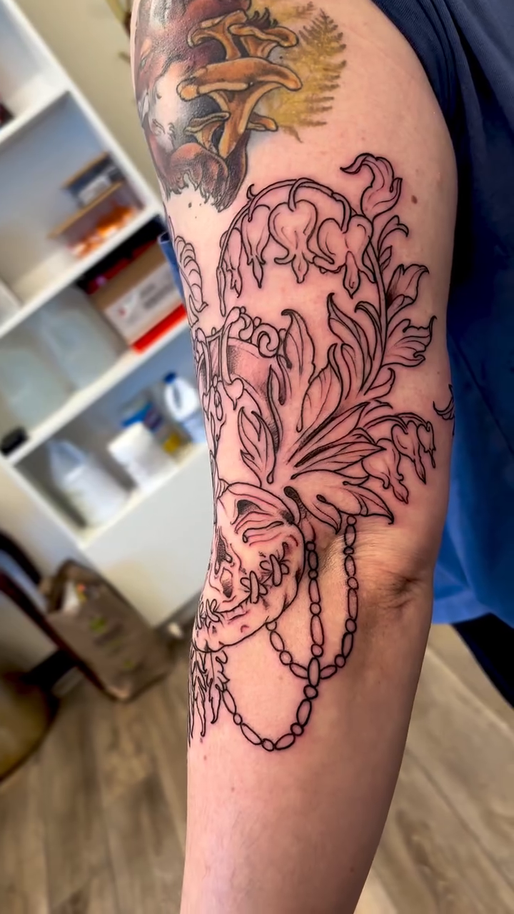 Skull with floral and chain elements ornamental tattoo on the forearm by Cricket Elijah Cervidae