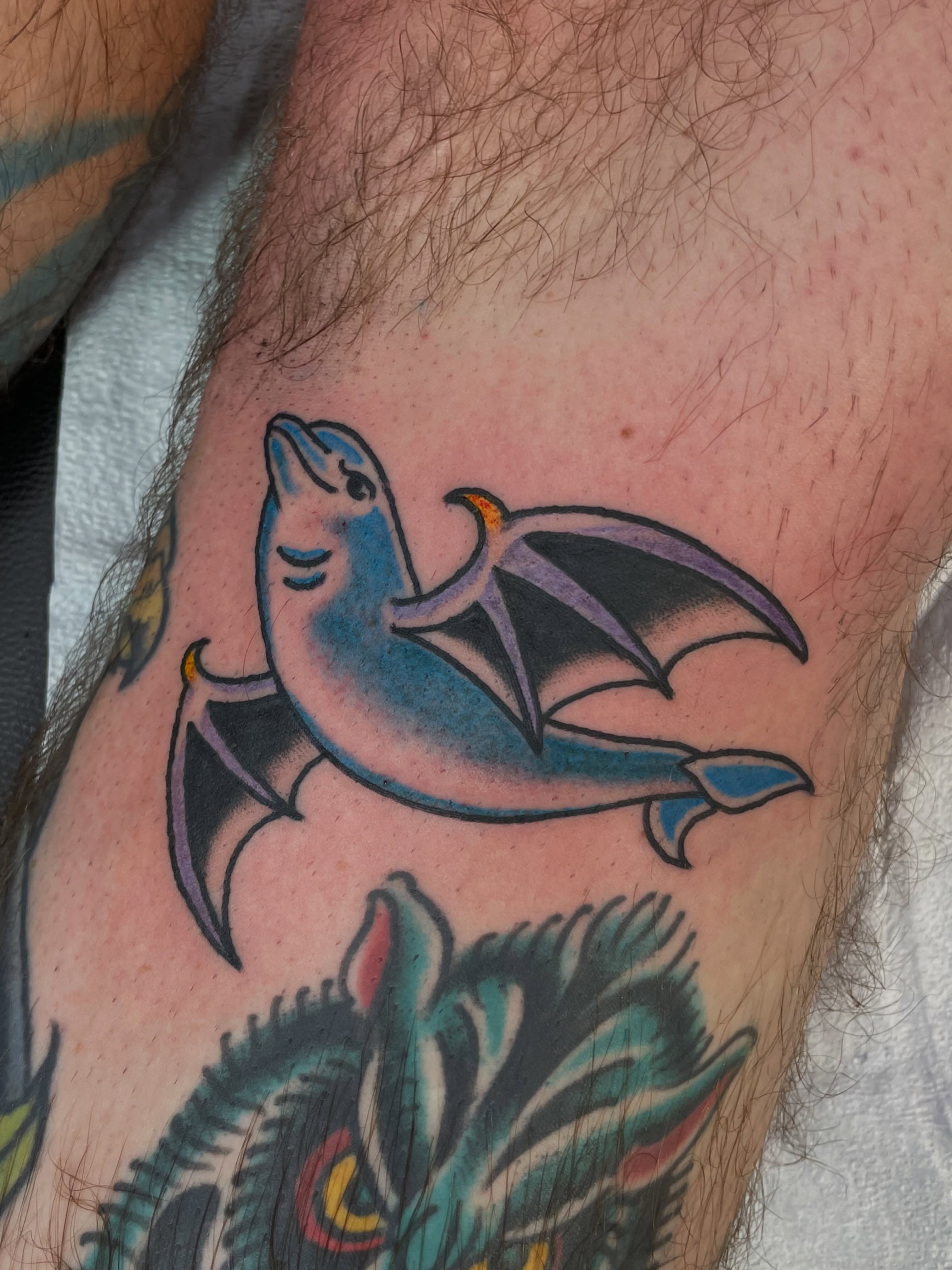 Dolphin with wings American traditional tattoo on the forearm by Greg De Hoot, Youngsville, North Carolina