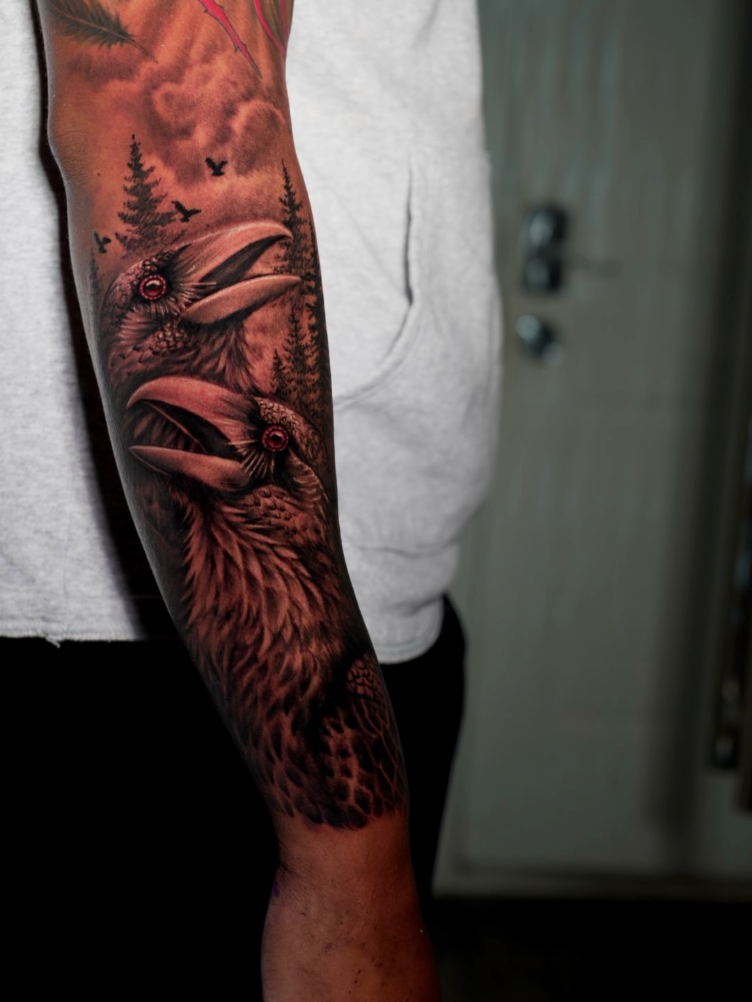 Two ravens in a forest realism tattoo on the forearm by Ethan Xu