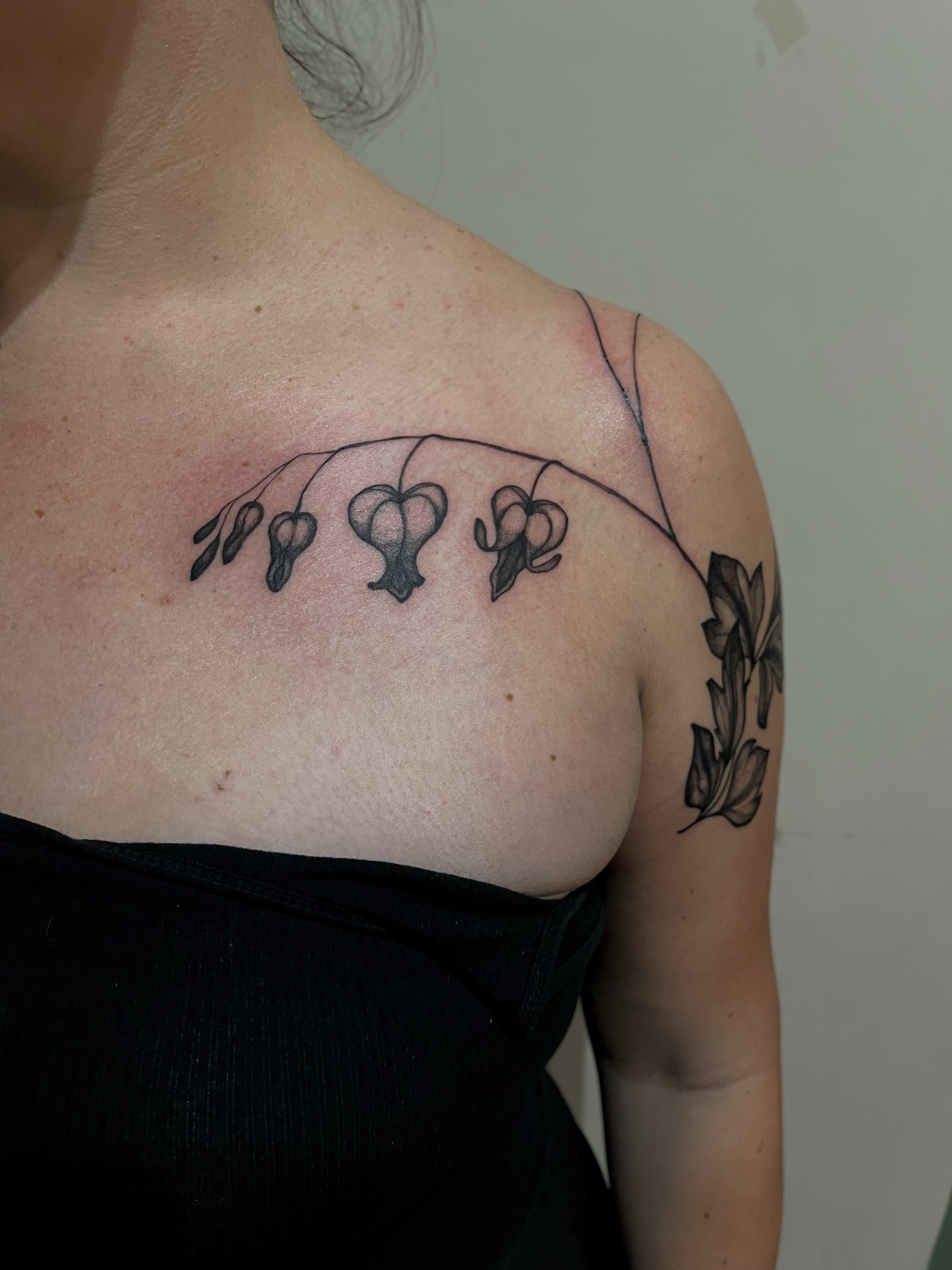 Heart-shaped flowers black and grey tattoo on the shoulder by Amy