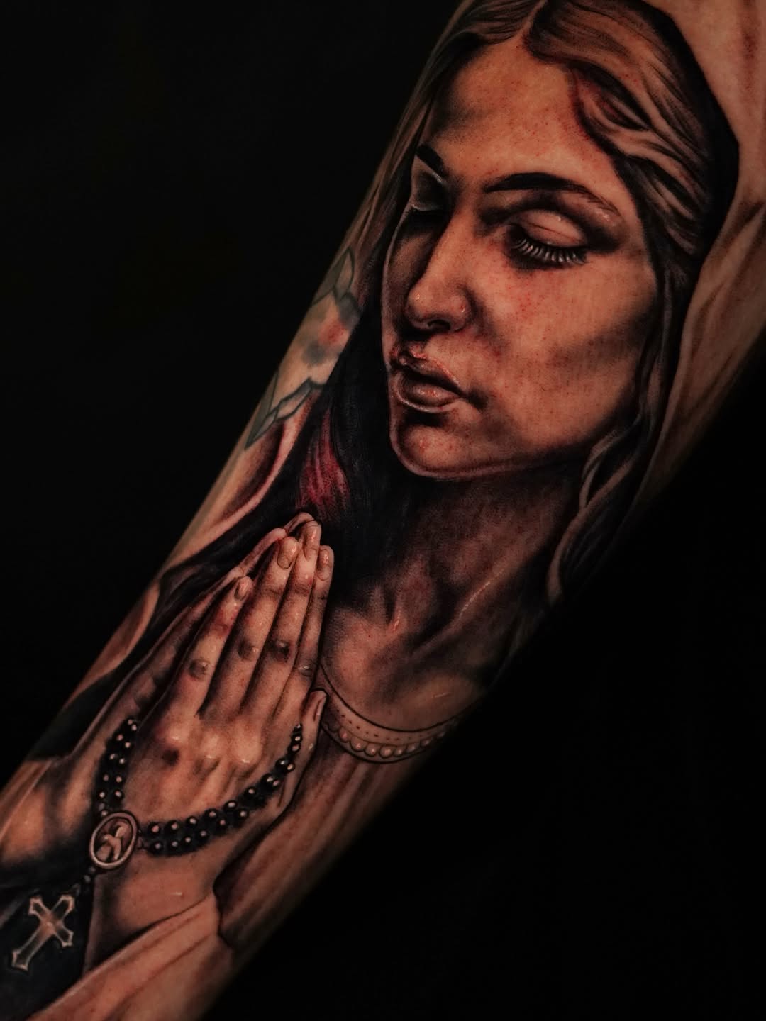 Woman praying with rosary Chicano tattoo on the forearm by Jennifer Garcia