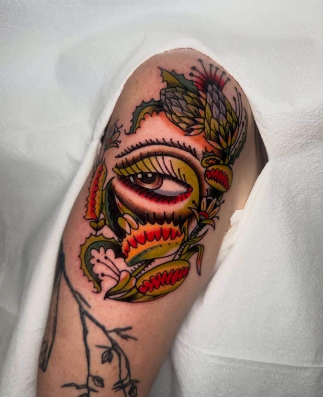 Eye and floral American traditional tattoo on the shoulder by Lexie Graff