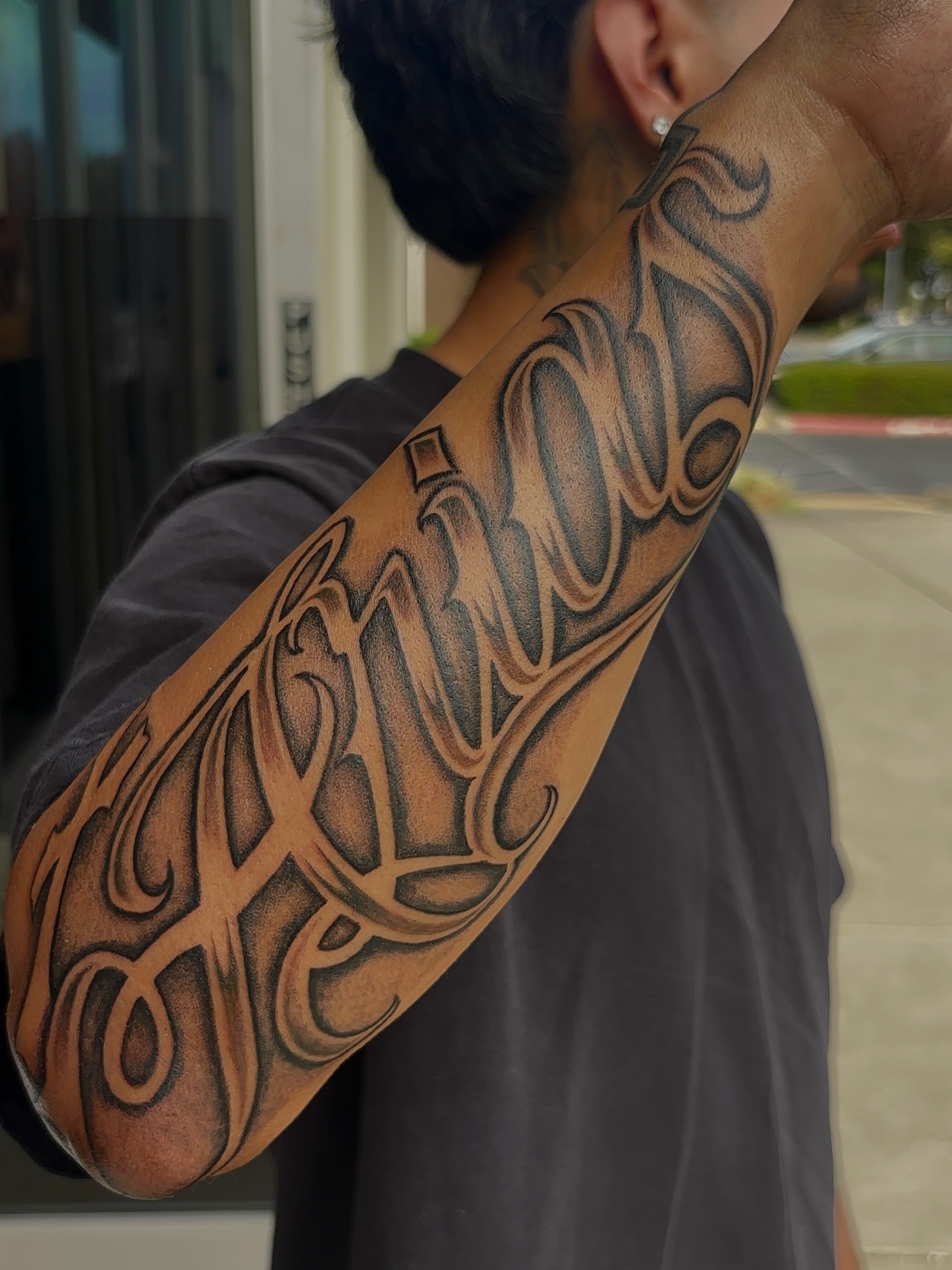 Script lettering lettering script tattoo on the upper arm by Cristiano Ochoa, Elk Grove, California