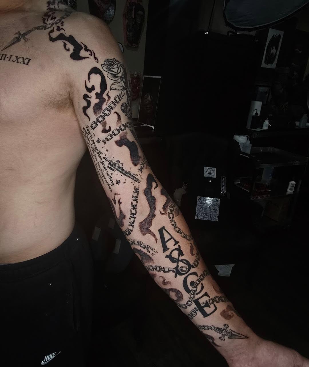 Chains and lettering black and grey tattoo on the forearm by Tucker