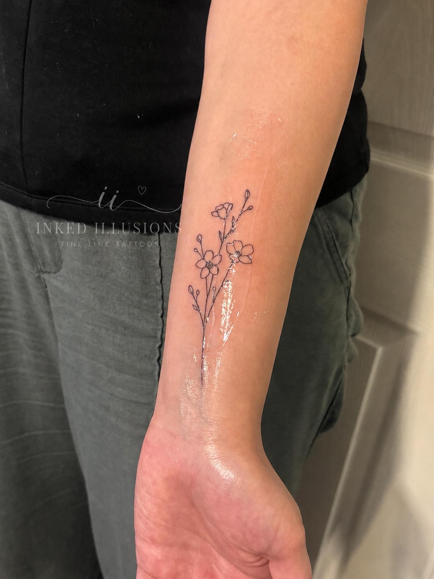 Flowers fine line tattoo on the forearm by Victoria Cooper