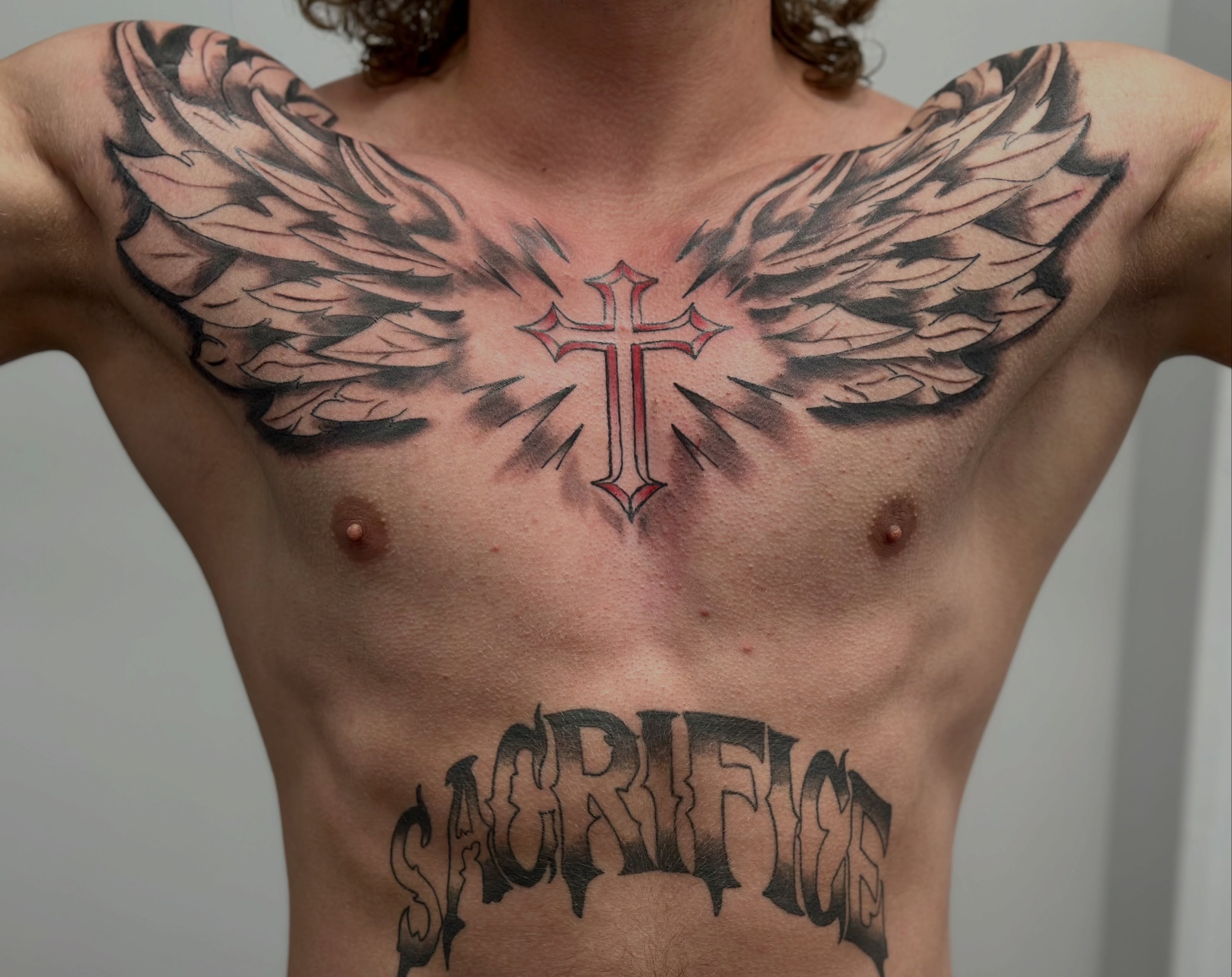 Cross with wings black and grey tattoo on the chest by AJ
