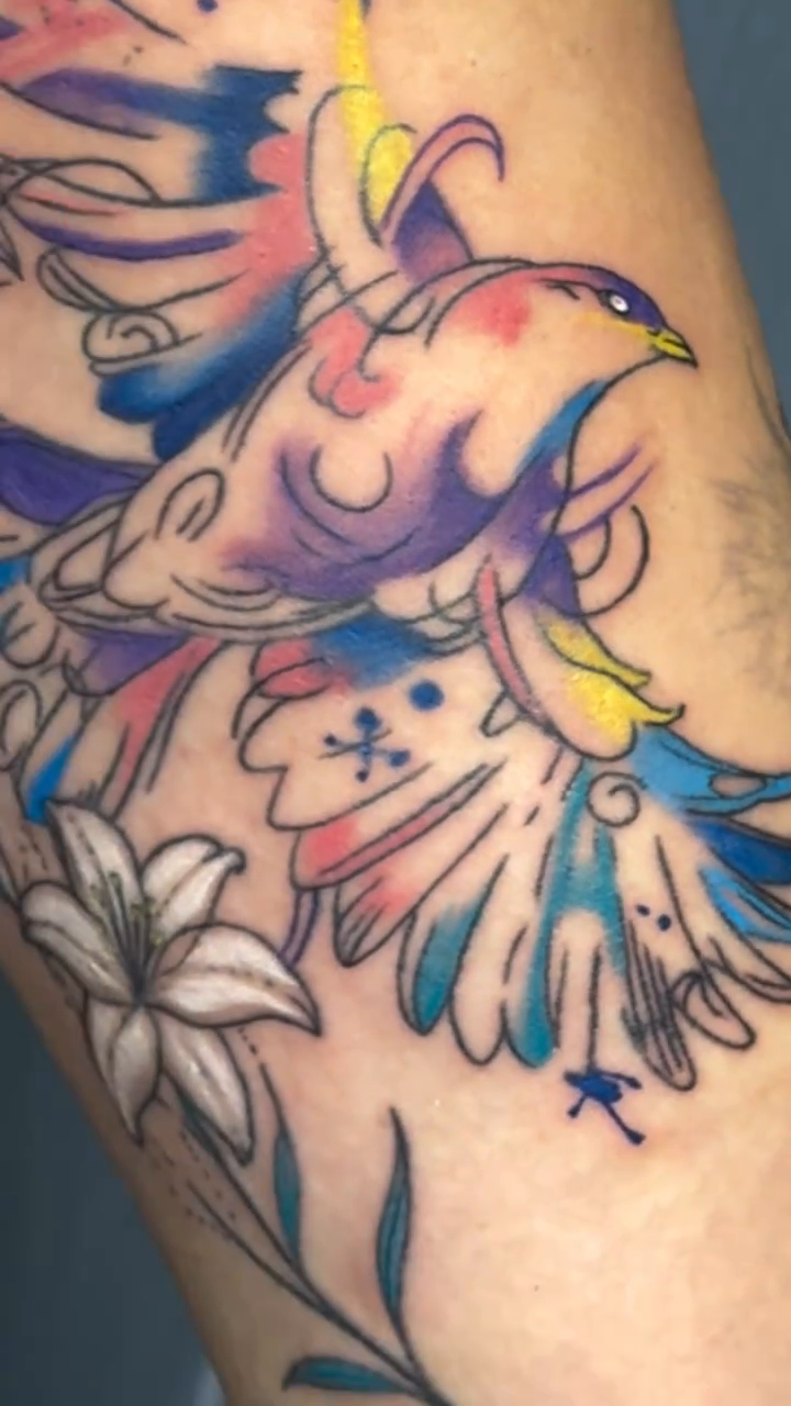 Bird with flowers watercolor tattoo on the forearm by Raciel Fabian Romero