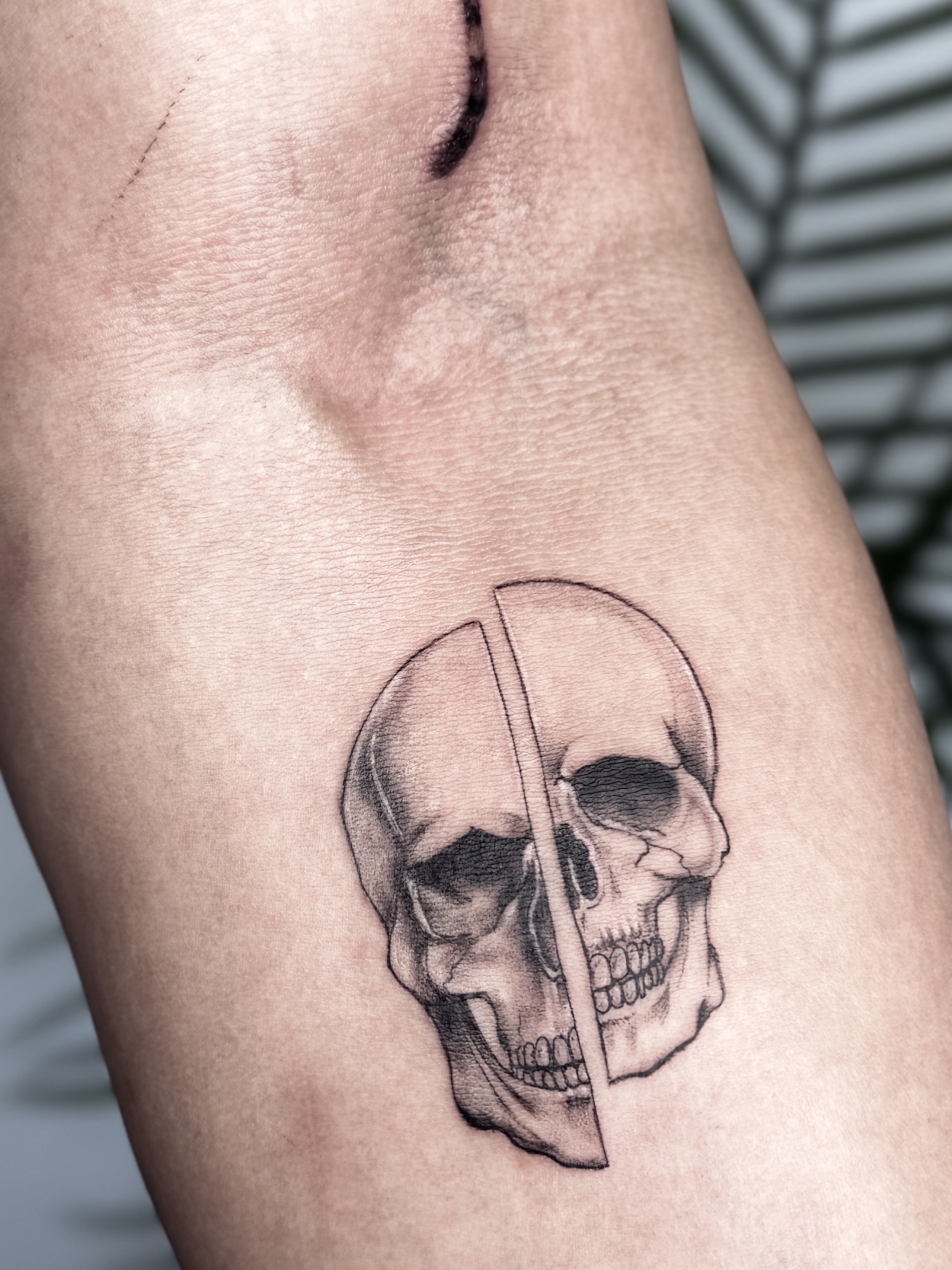 Skull black and grey tattoo on the forearm by Tatuajes Denver