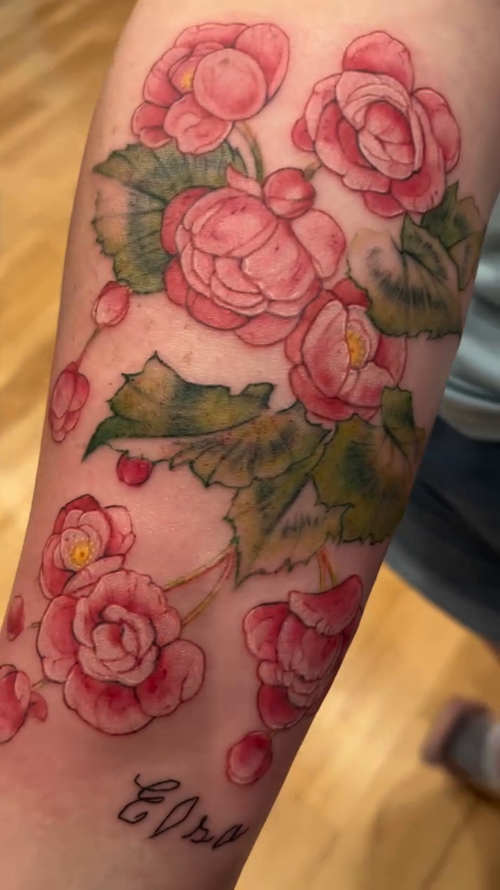 Pink flowers with green leaves neo-traditional tattoo on the forearm by Rachel Walker