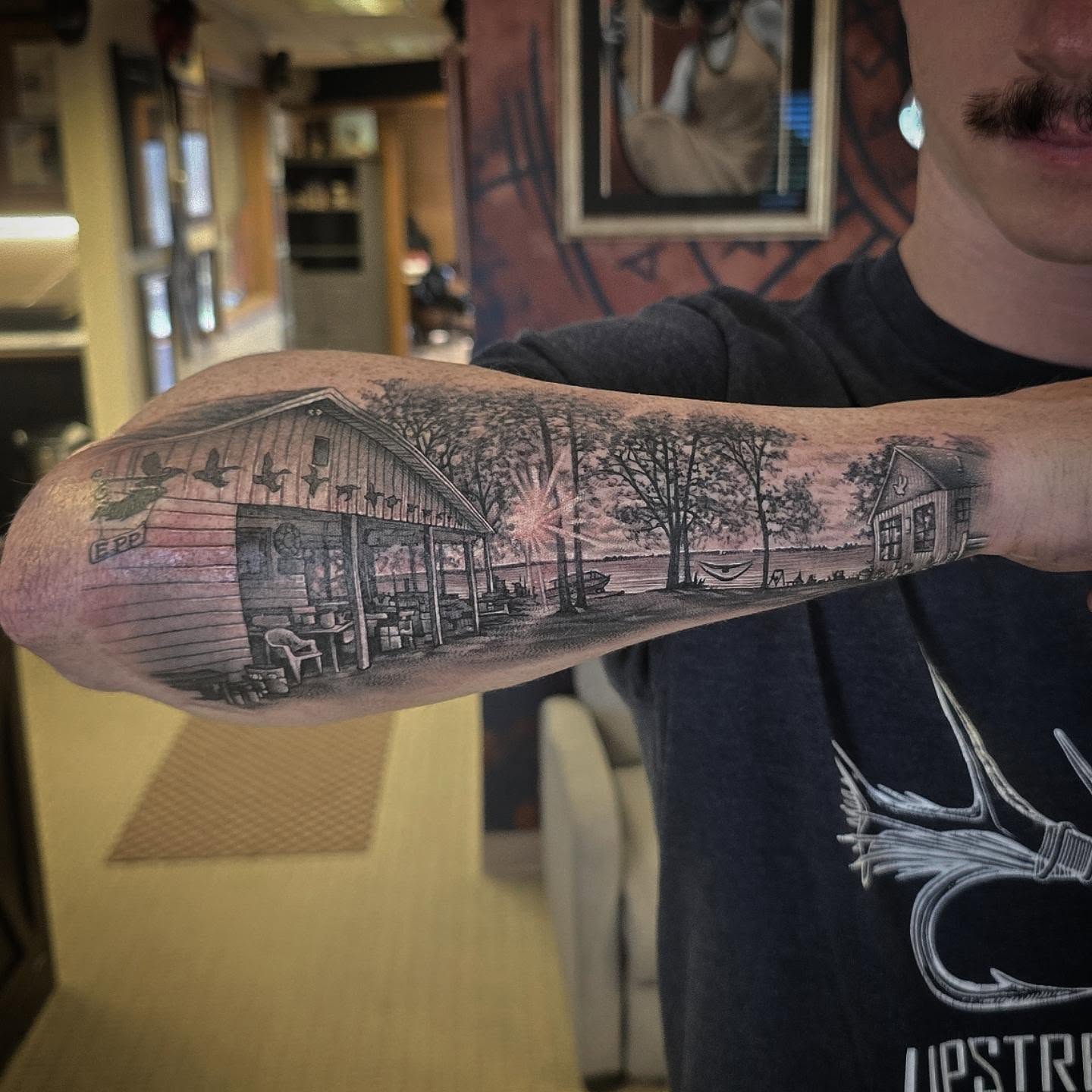 Lake cabin realism tattoo on the forearm by Alexander L. Wolff, Rapid City, South Dakota